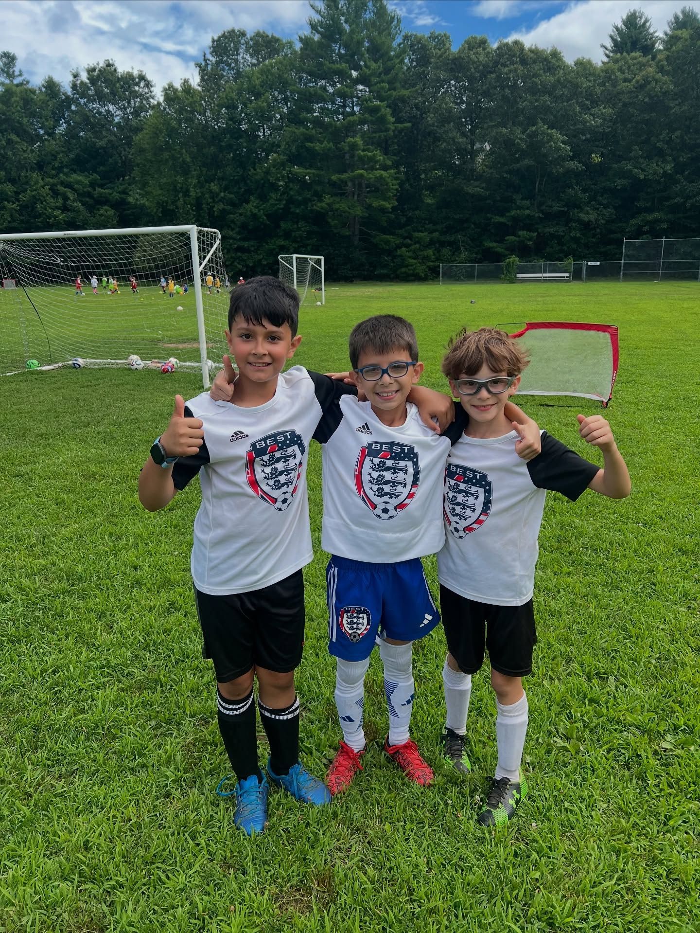 Three BEST FC players in soccer jerseys pose on a field