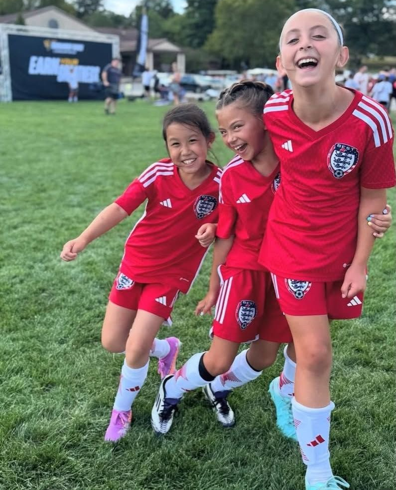 Three BEST FC soccer players in red uniforms smiling