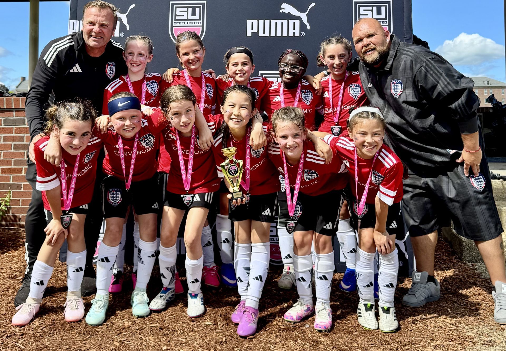 BEST FC soccer team posing with coaches, wearing medals 