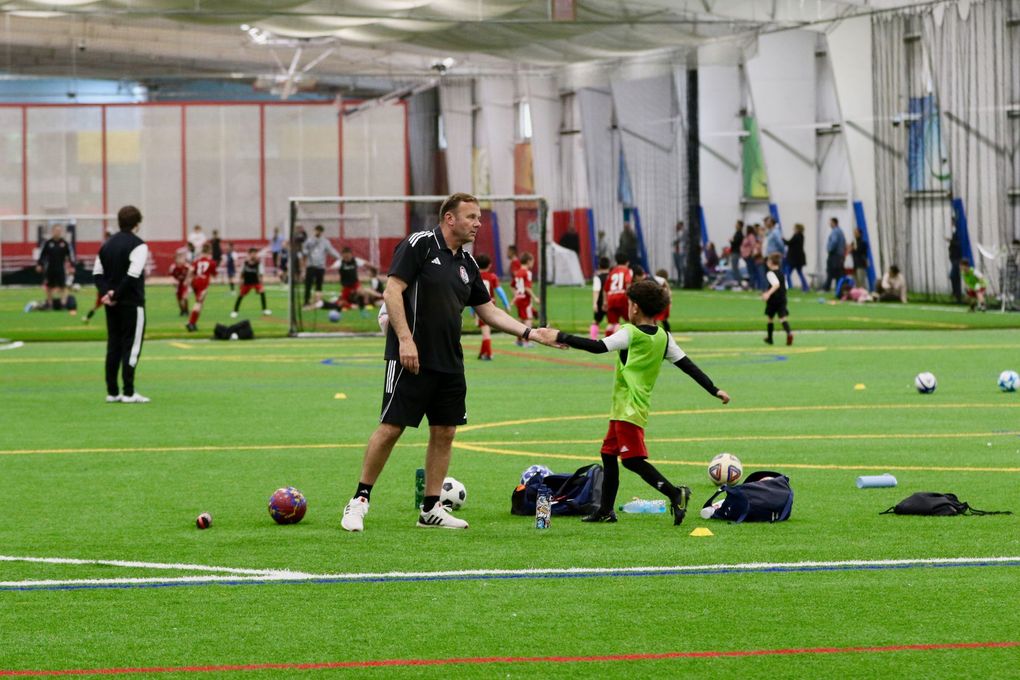 BEST FC coach giving a high five to a player on an indoor turf field