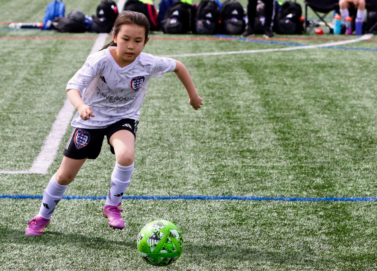 BEST FC player dribbling a soccer ball on a field during practice
