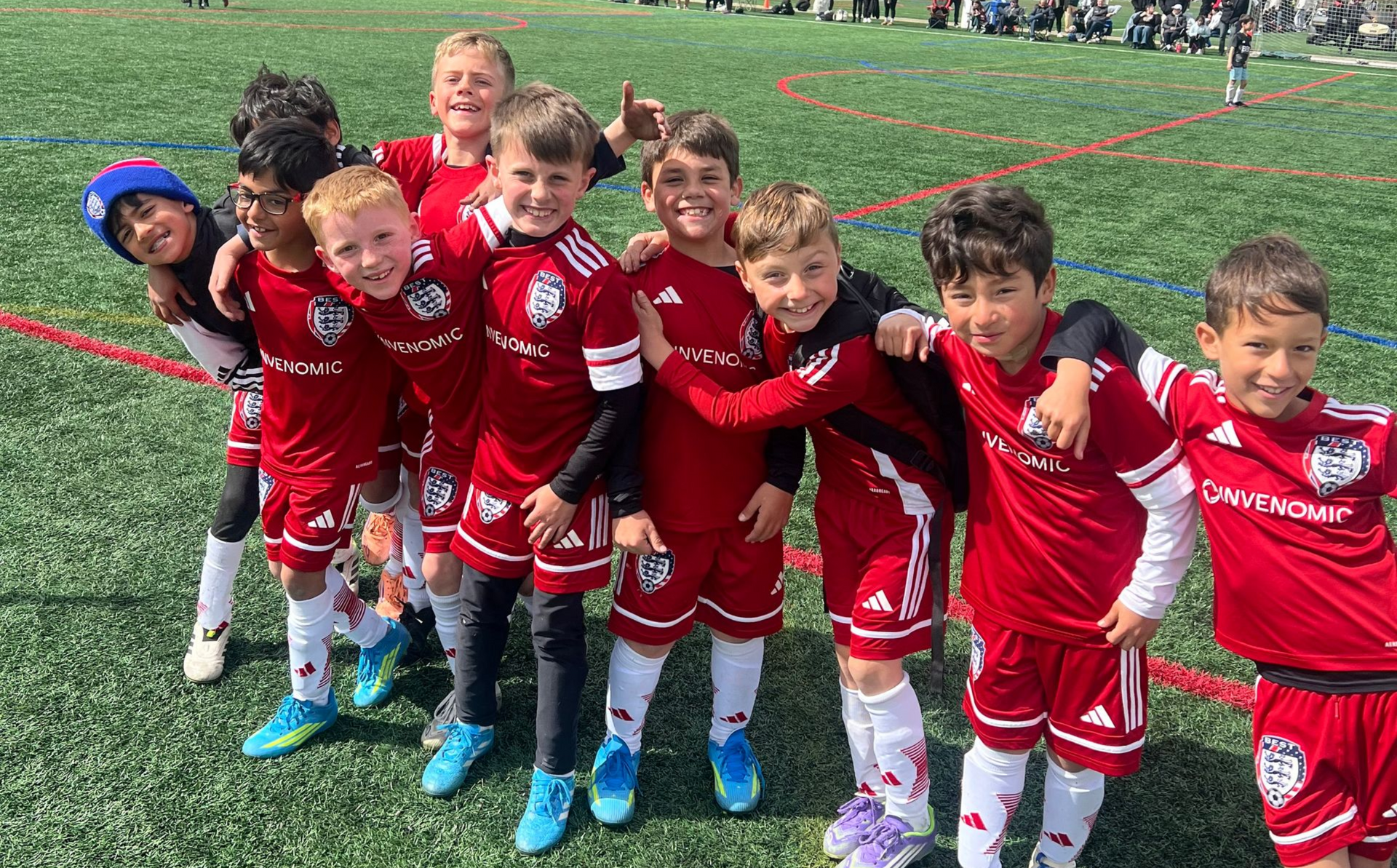 BEST FC soccer team in red uniforms posing together on a field