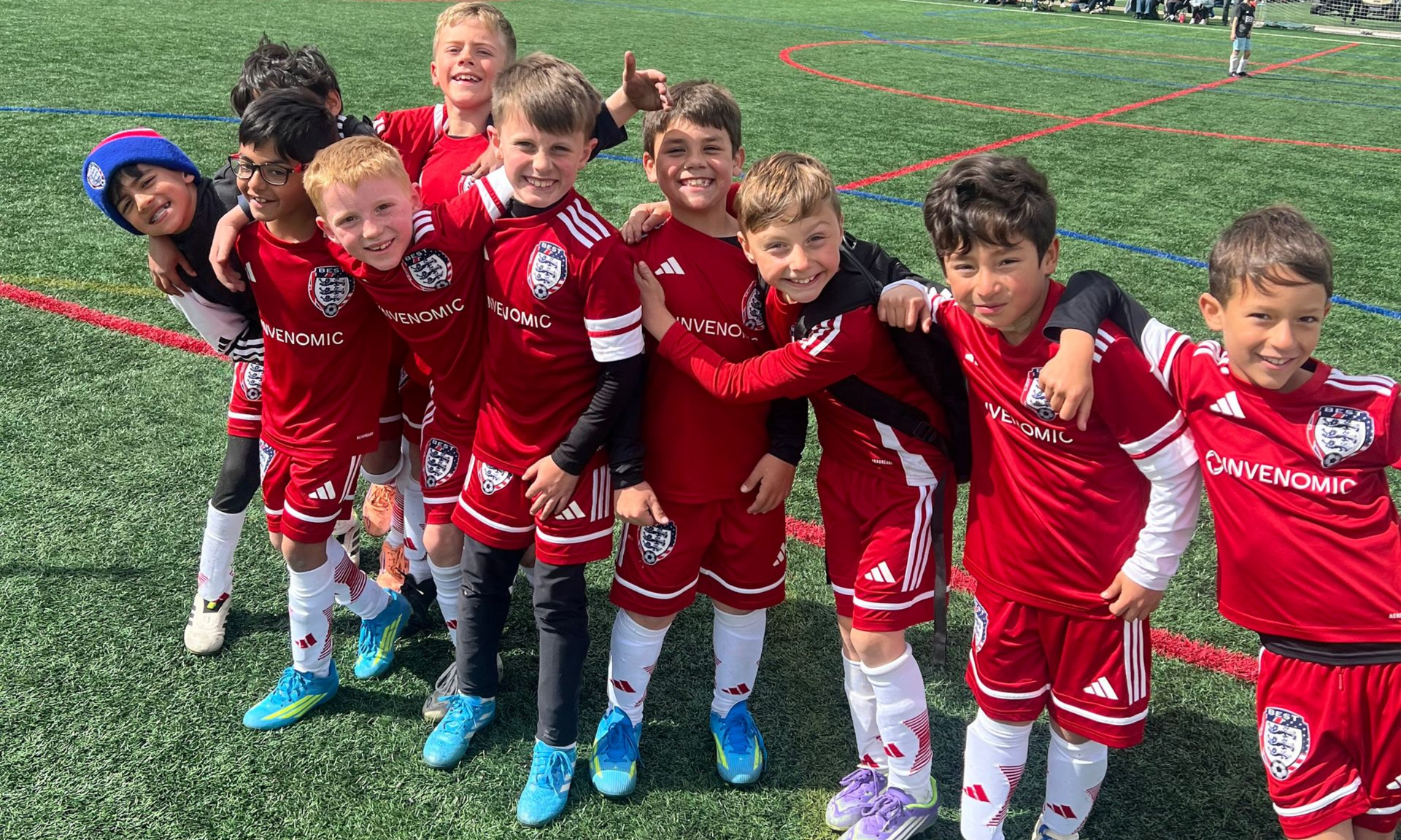 BEST FC soccer team in red uniforms posing together on a field