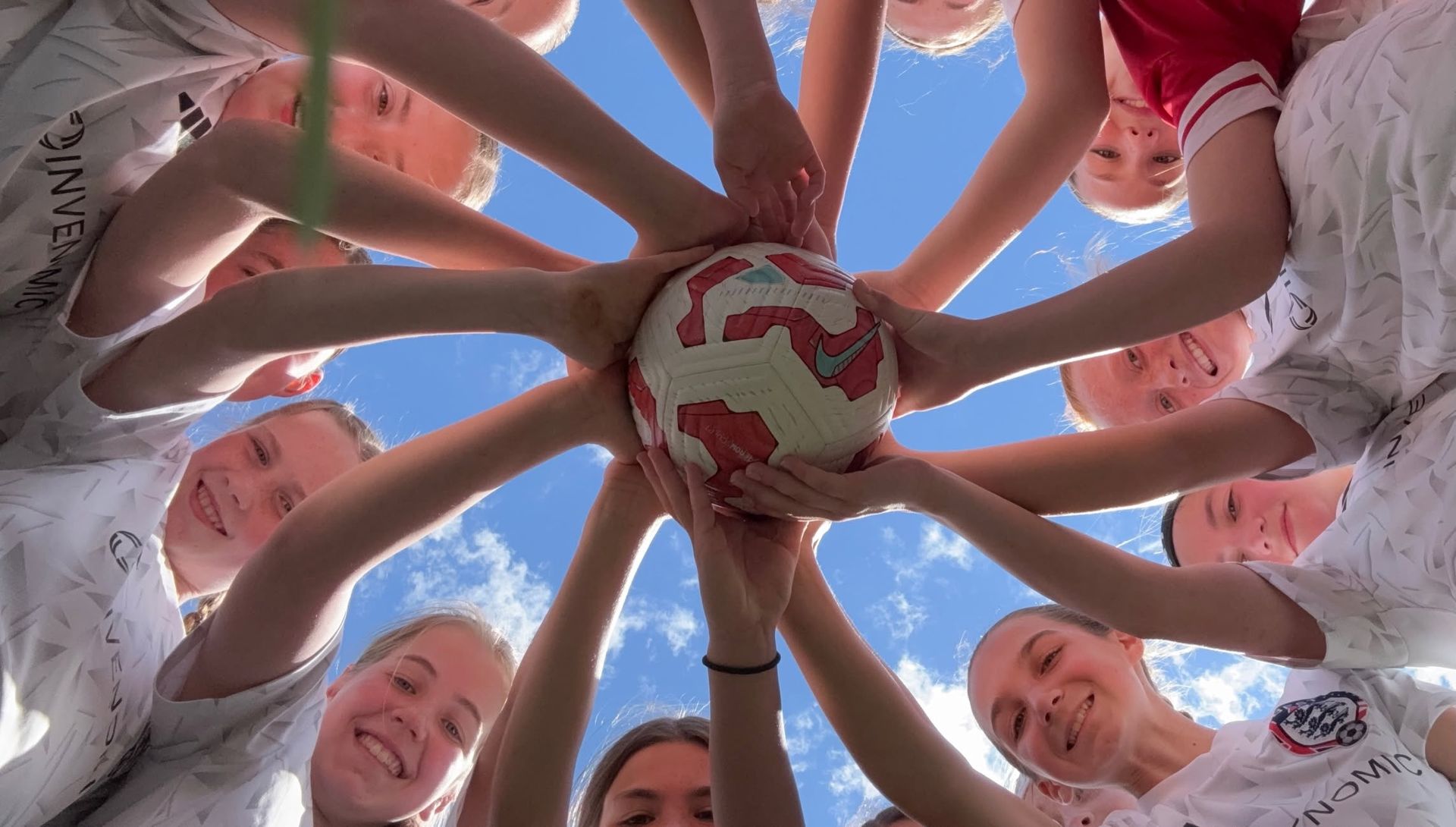 BEST FC team in a huddle with hands stacked on a soccer ball