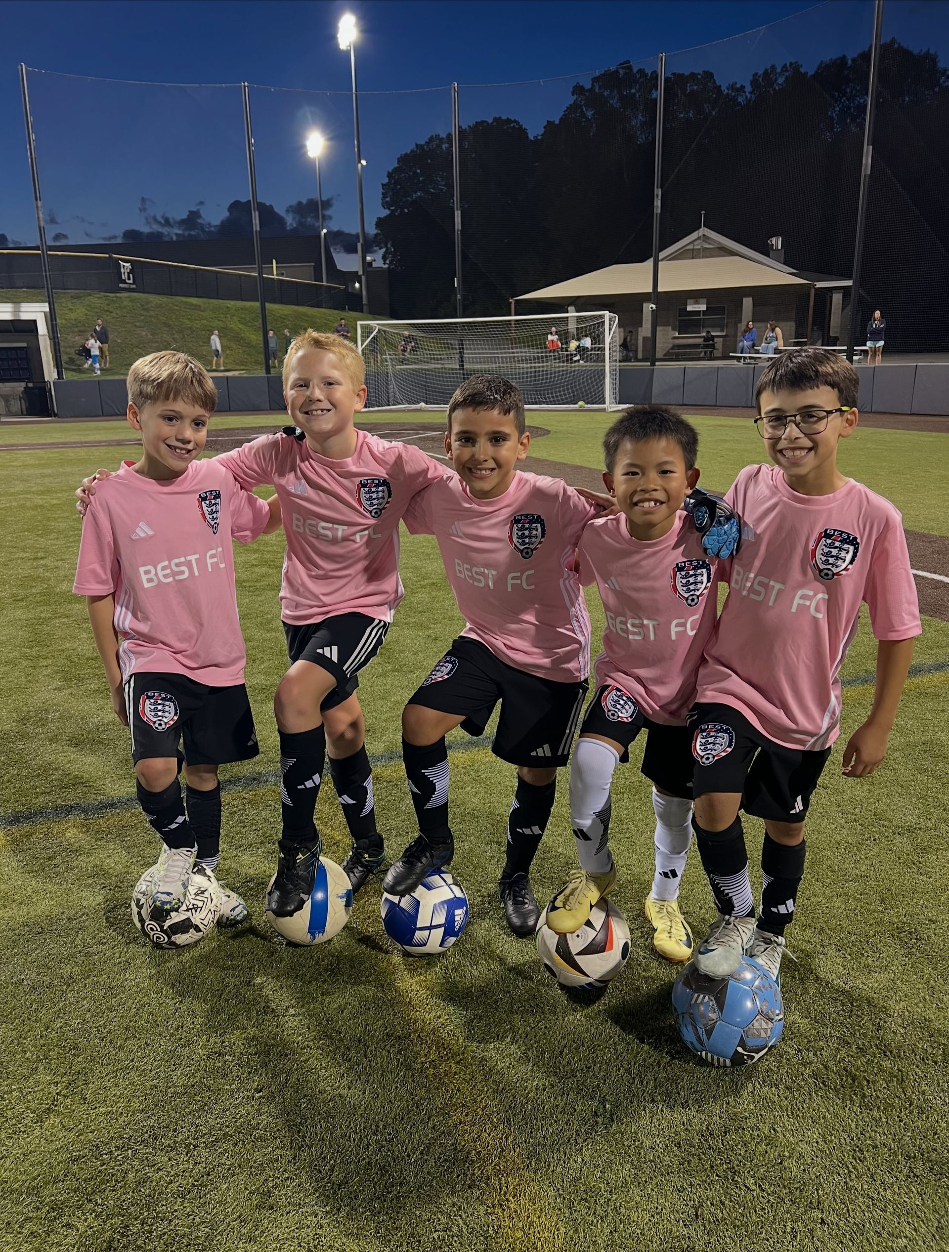 BEST FC youth soccer players in pink jerseys pose on a field