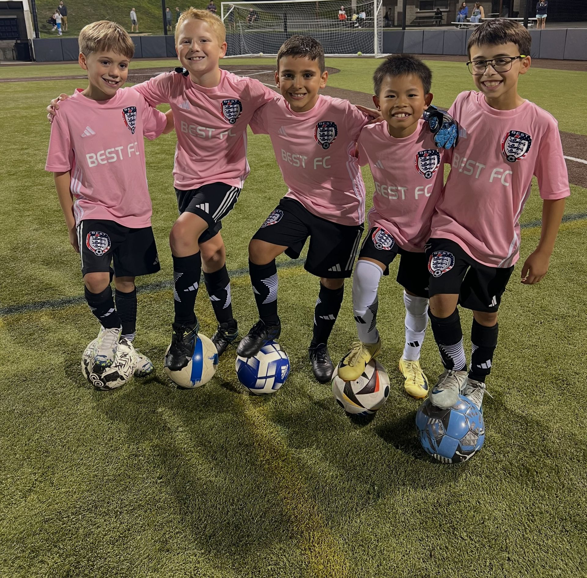 BEST FC youth soccer players in pink jerseys pose on a field
