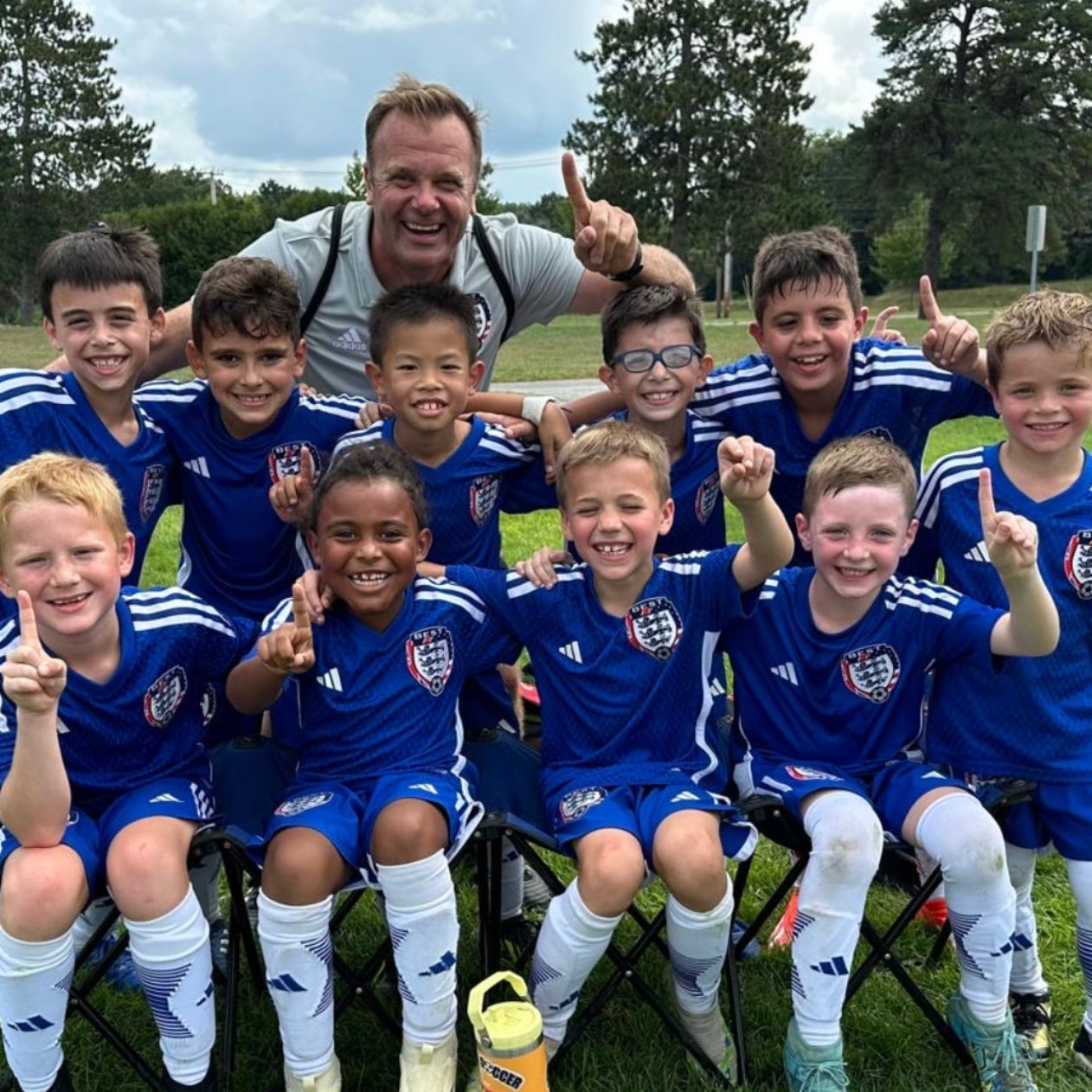 BEST FC  soccer team in blue jerseys posing with a coach