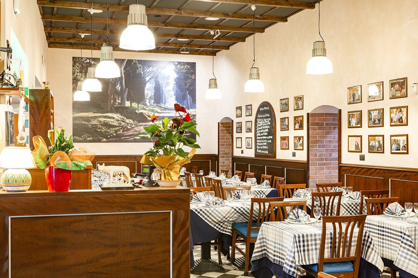 L'interno accogliente di un ristorante, con tavoli apparecchiati con tovaglie a quadri blu e bianchi e lampade a sospensione.