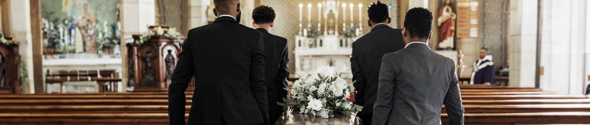 Four African American pallbearers carrying a casket down the aisle of a funeral chapel
