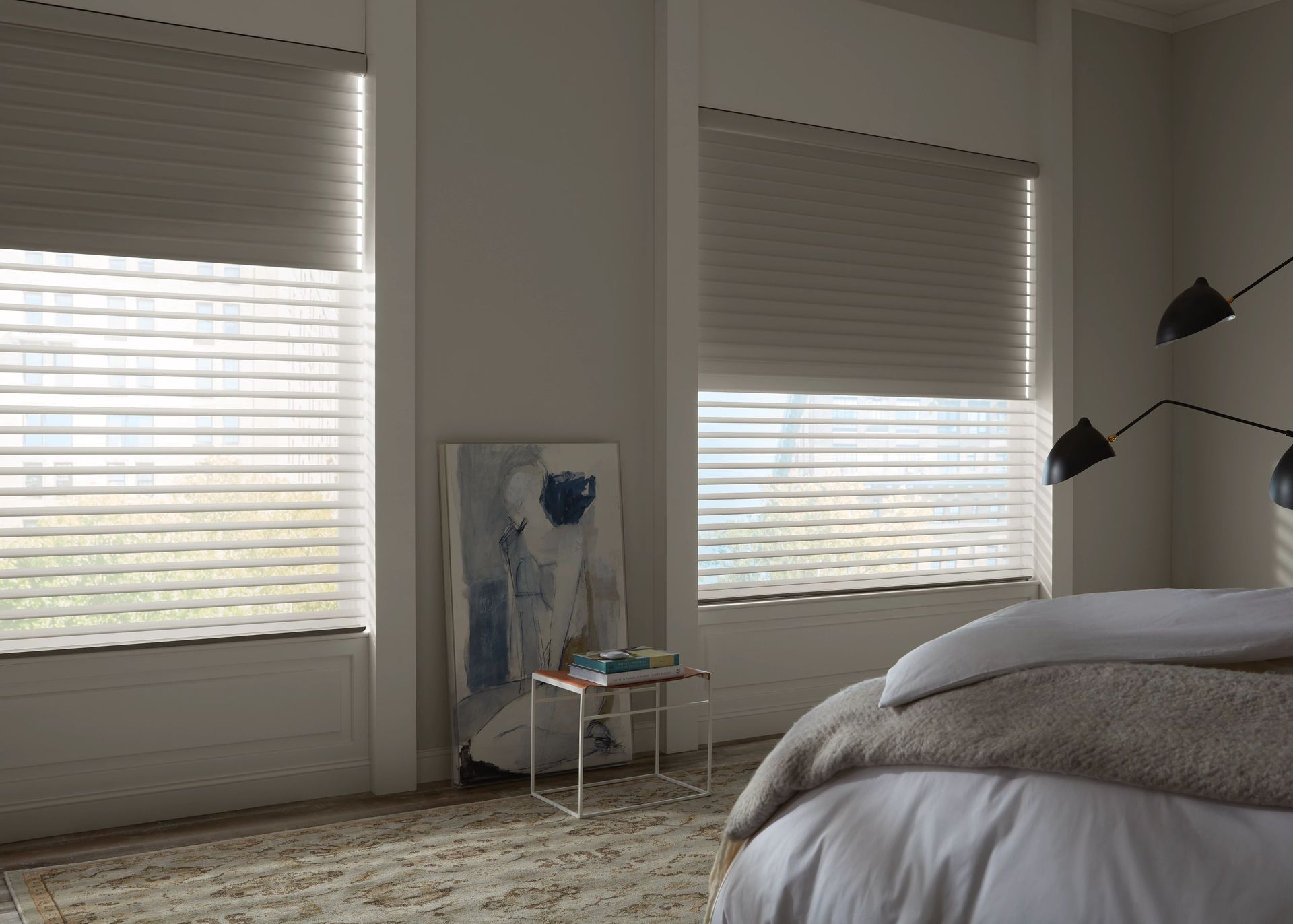 Bedroom with sheer horizontal blinds, white walls, and a bed with light-colored bedding.