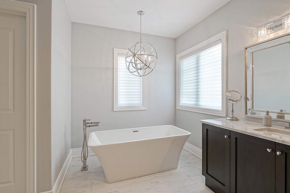 Modern bathroom with white tub, dark vanity, and light gray walls.