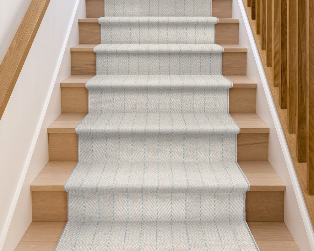 Staircase with light beige carpet runner, natural wood steps and railings.