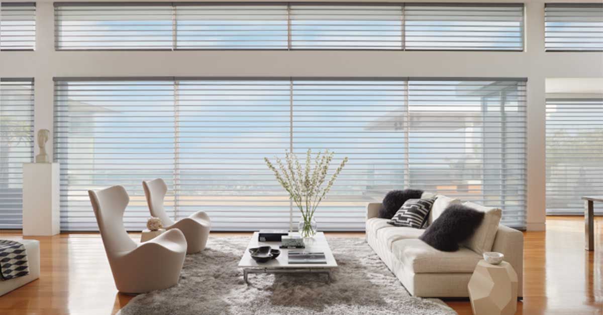 Modern living room with sheer horizontal blinds; cream furniture, hardwood floors, and a view.