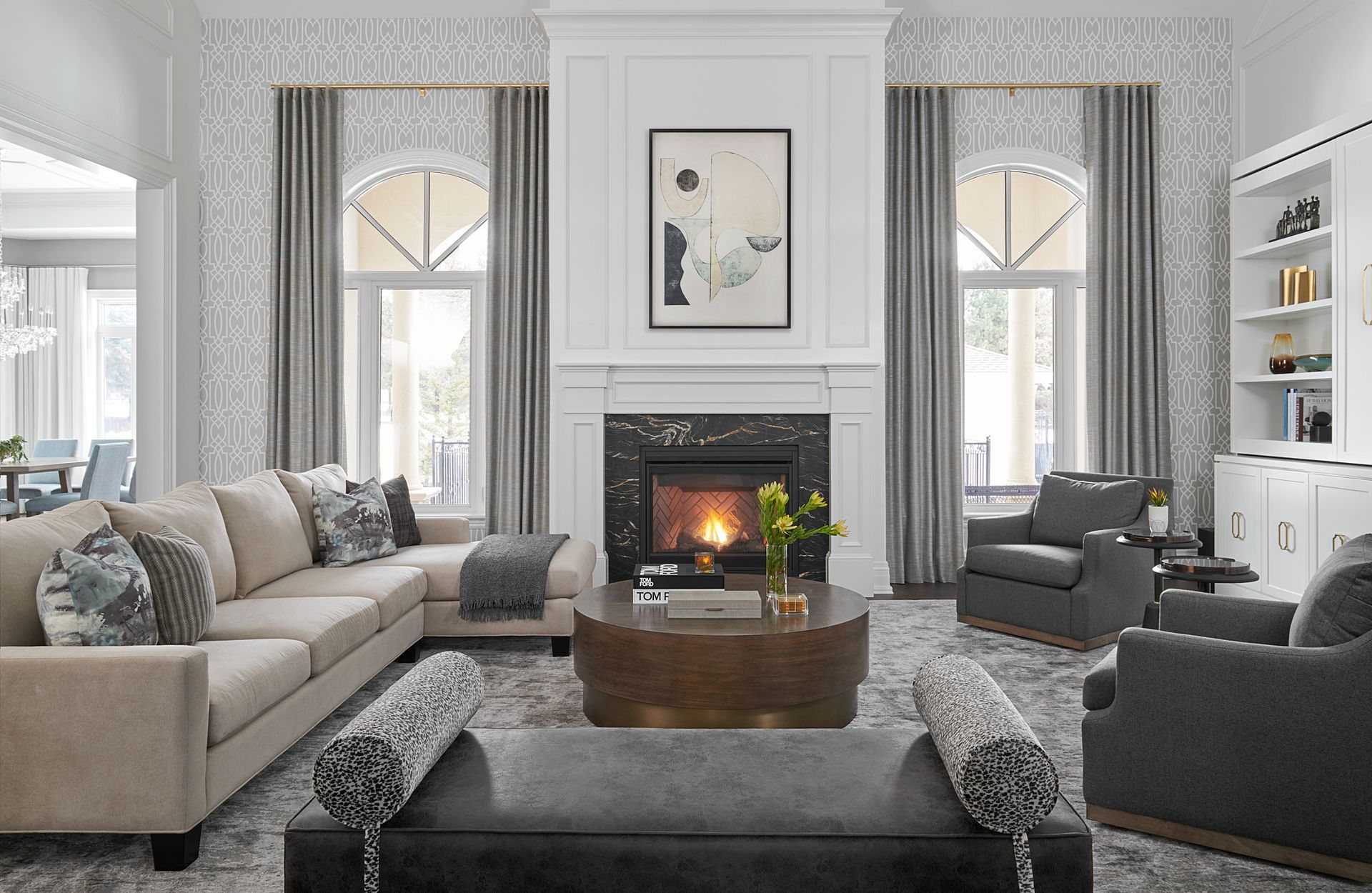 Elegant living room with fireplace, beige sectional sofa, and gray armchairs; neutral color palette.