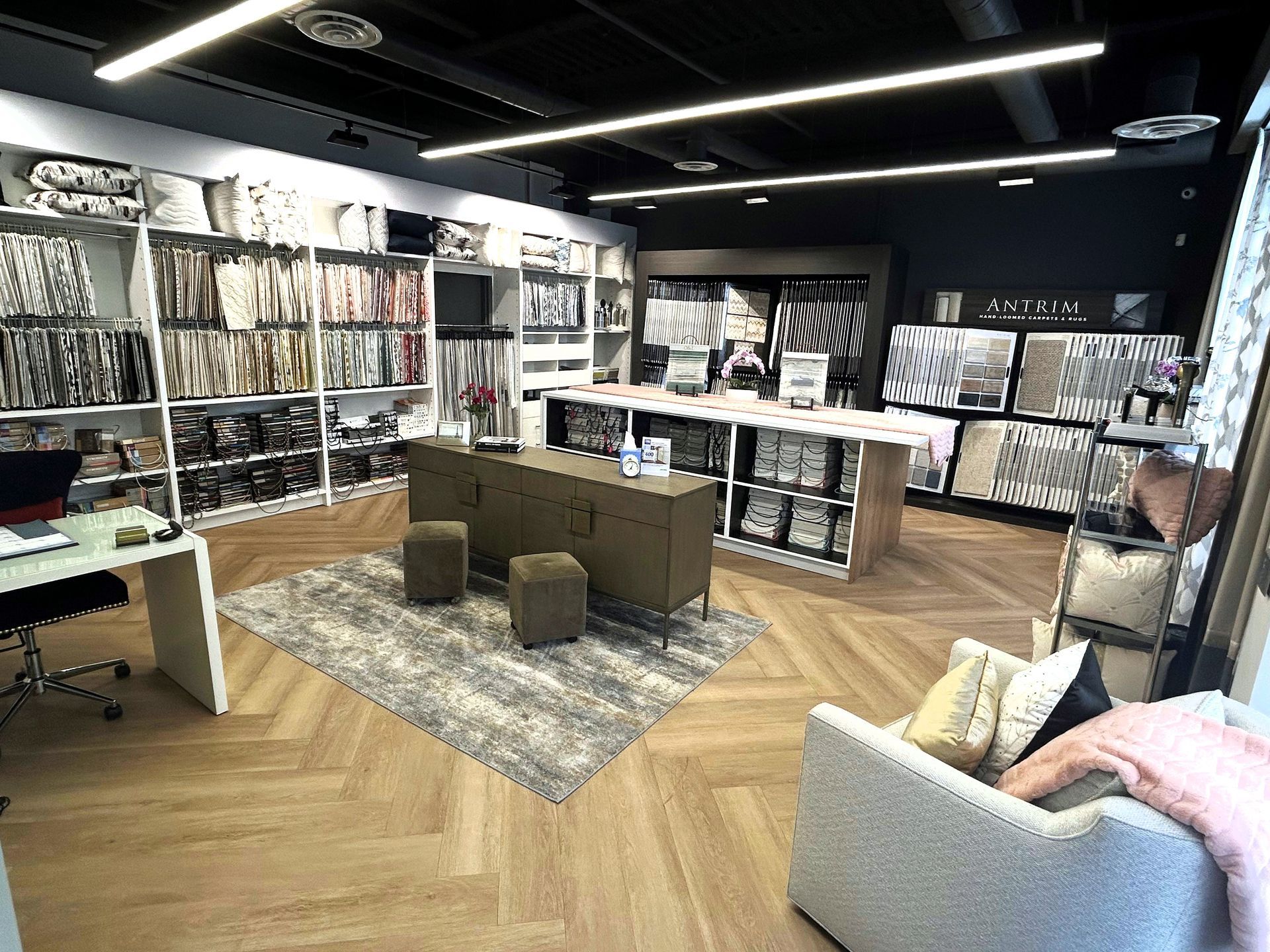 Interior of a fabric store, with shelves of fabric samples, a display table, and seating.