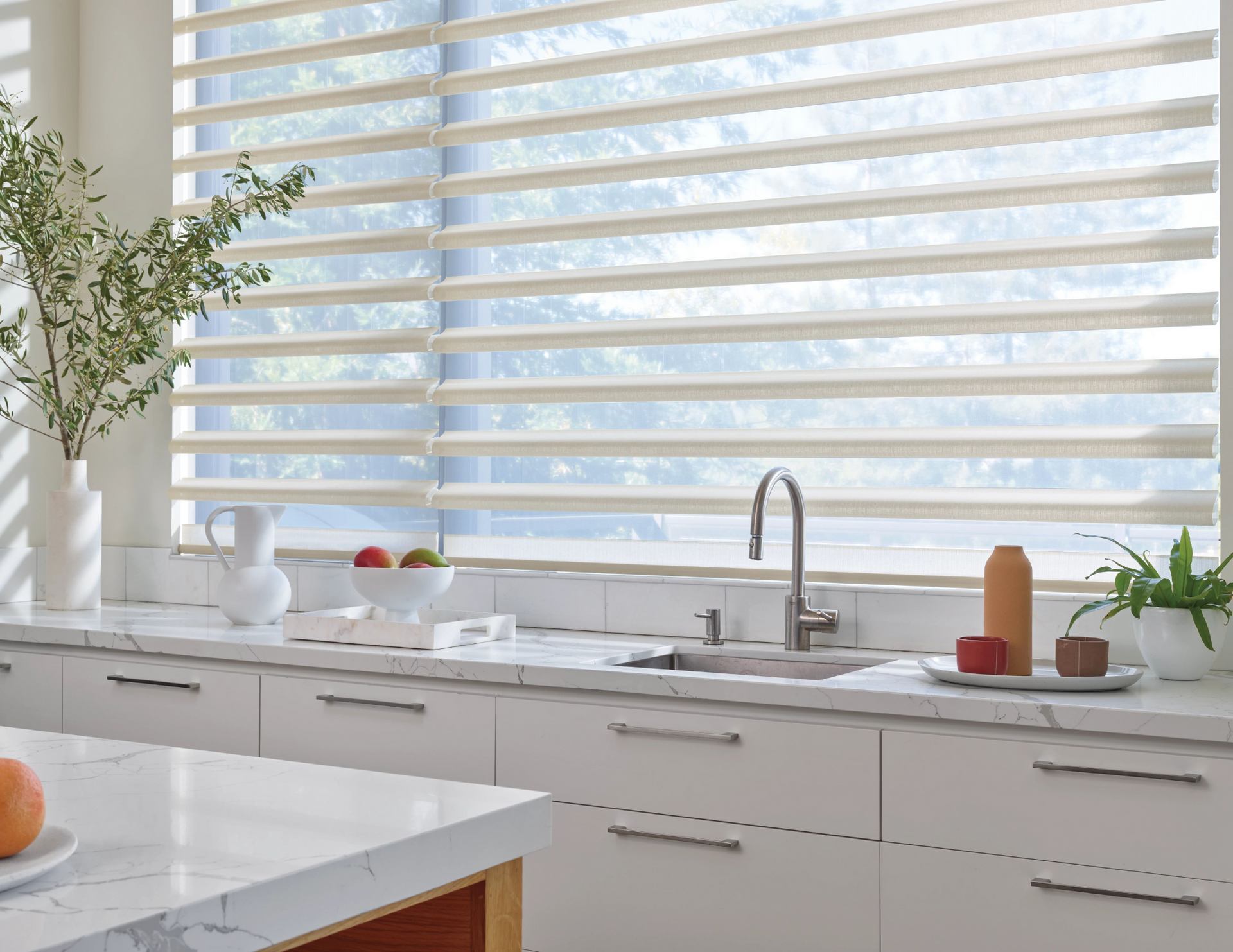 Kitchen with open horizontal window blinds over a sink and white cabinets.