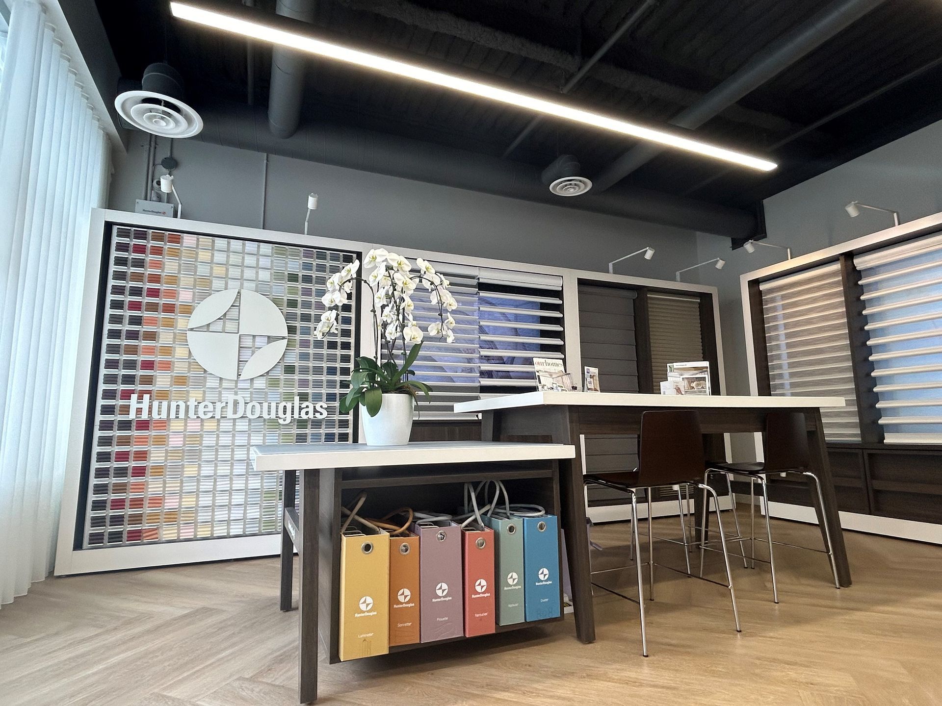 Interior showroom featuring Hunter Douglas window coverings, display table, and samples.
