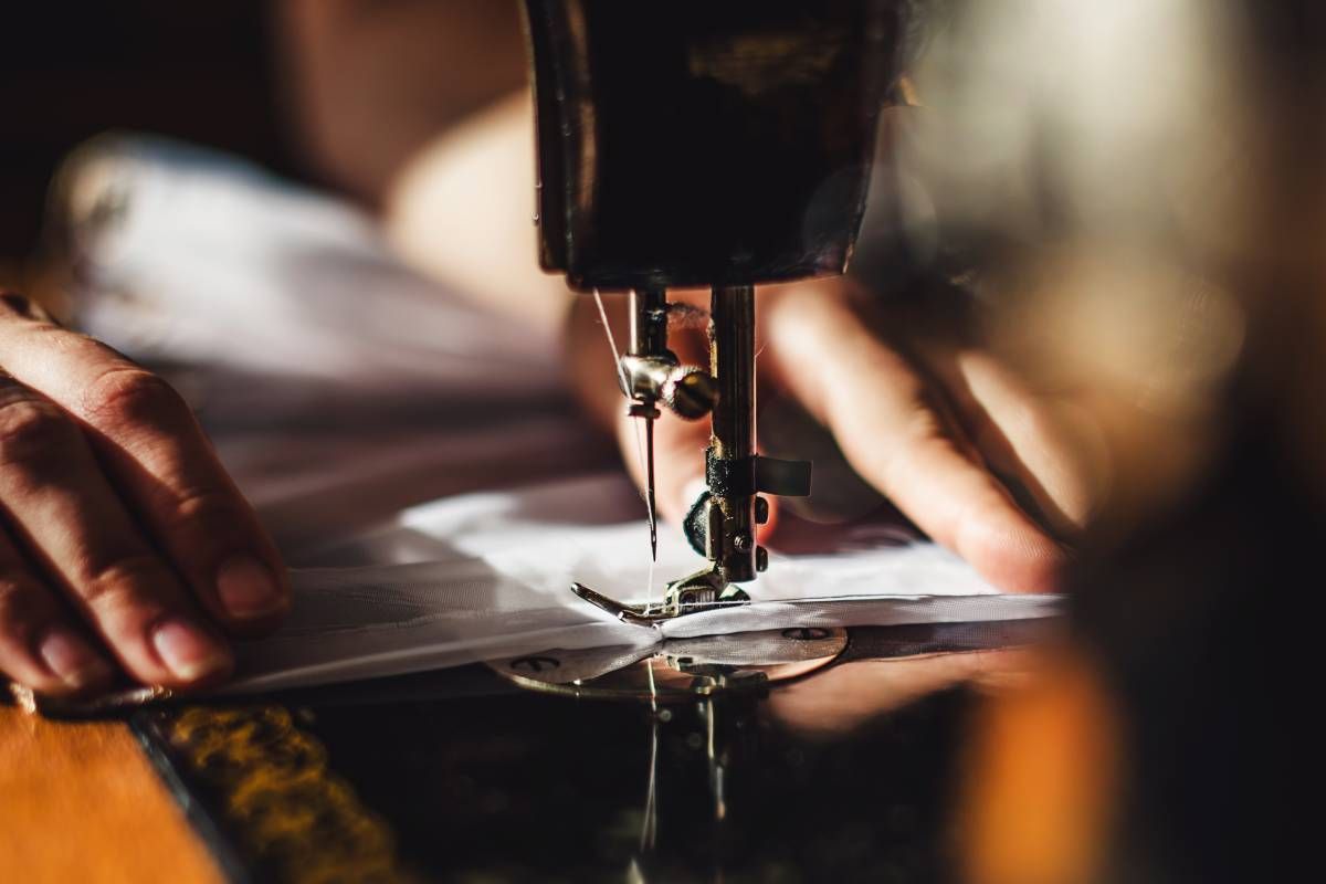 An upclose image of a sewing machine and a sewist working in the custom workroom
