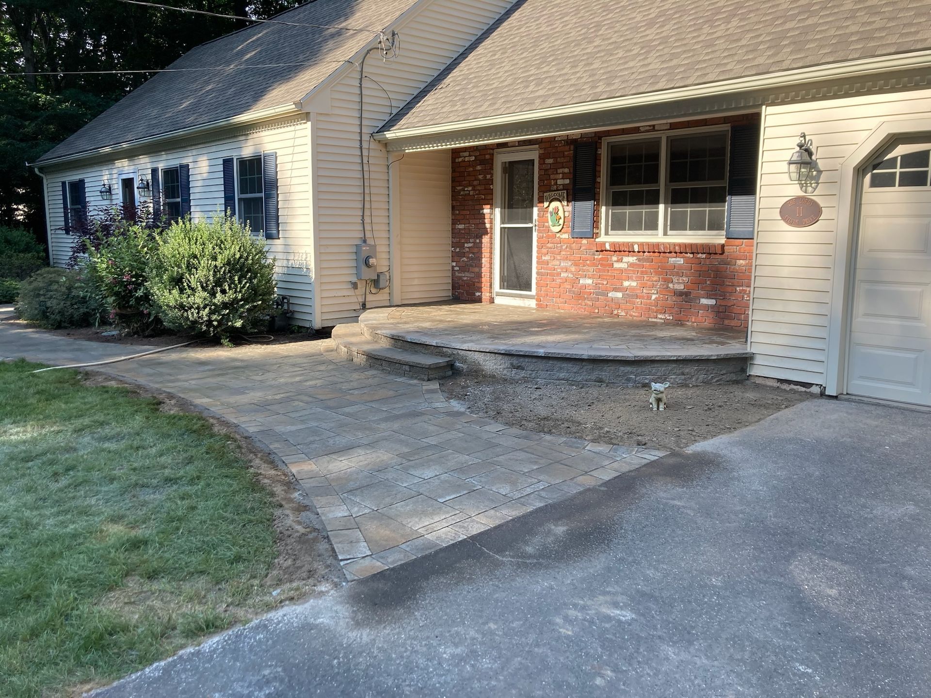 Brick home exterior with paved walkway and steps leading to the front door, next to a garage.