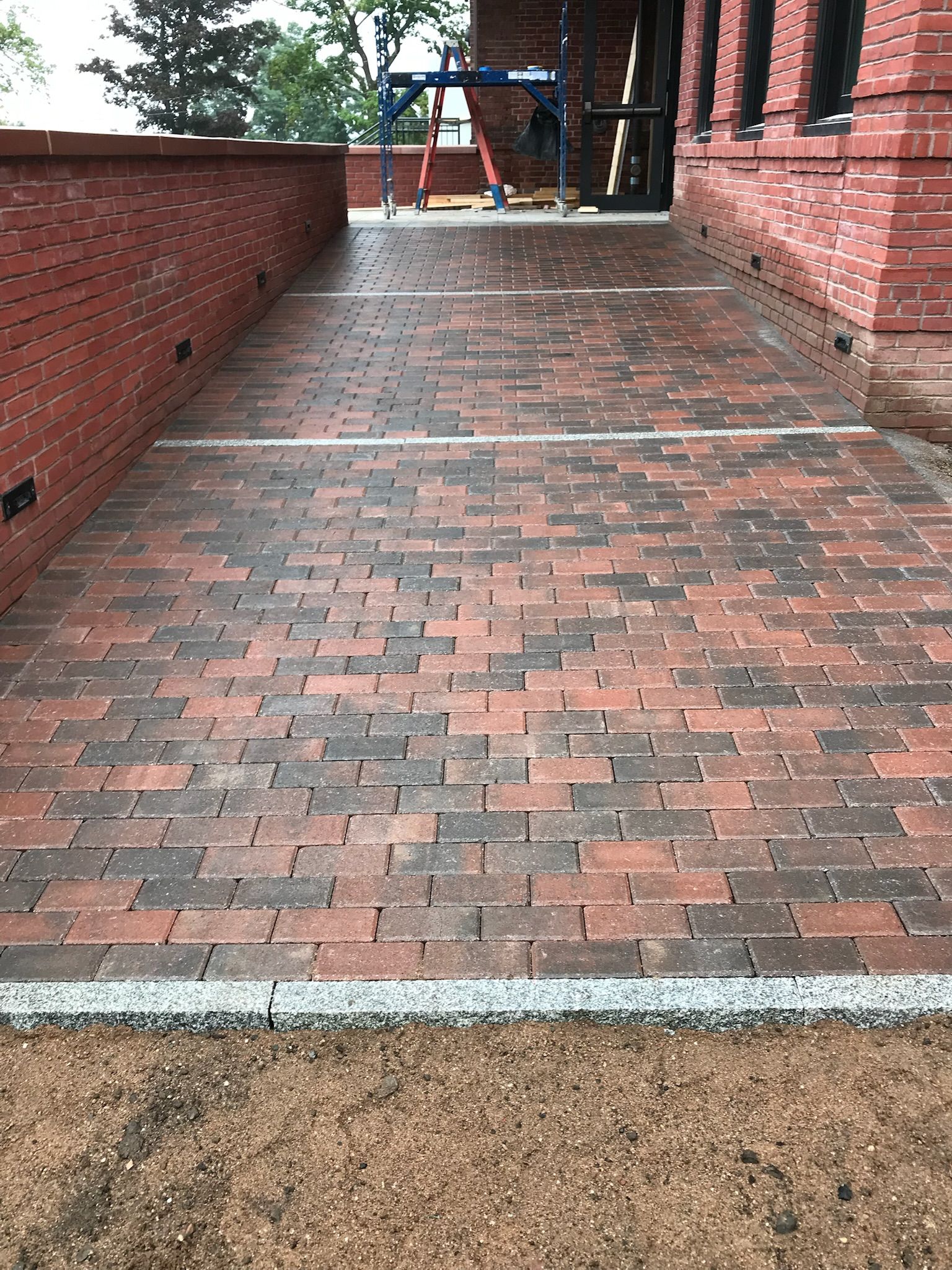 Brick walkway with red bricks and white accents, leading towards a building entrance.