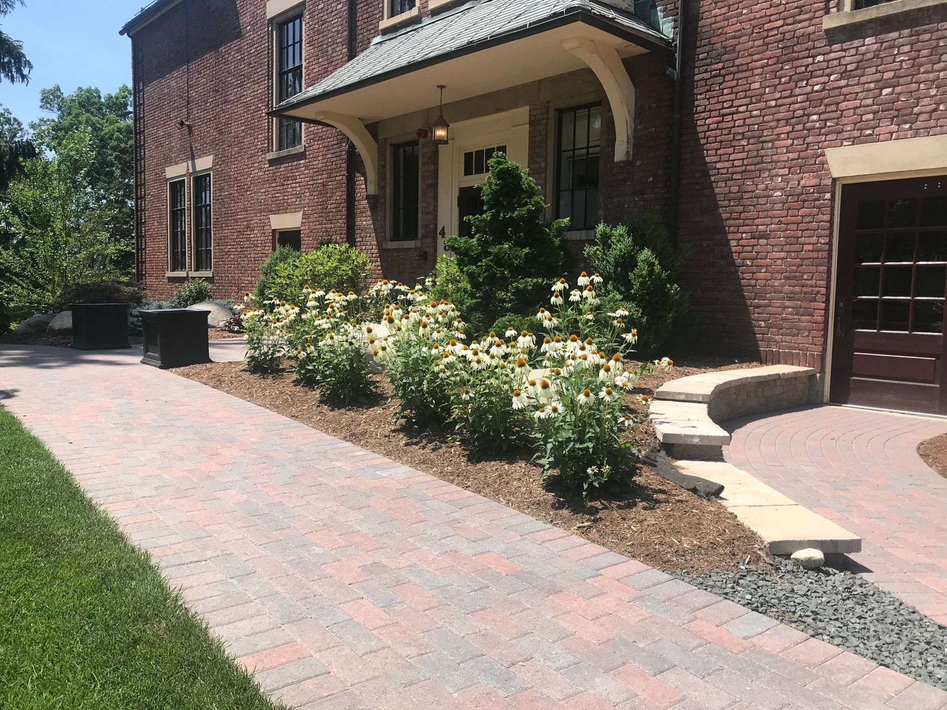 Red brick building with a brick walkway and landscaped flower bed.