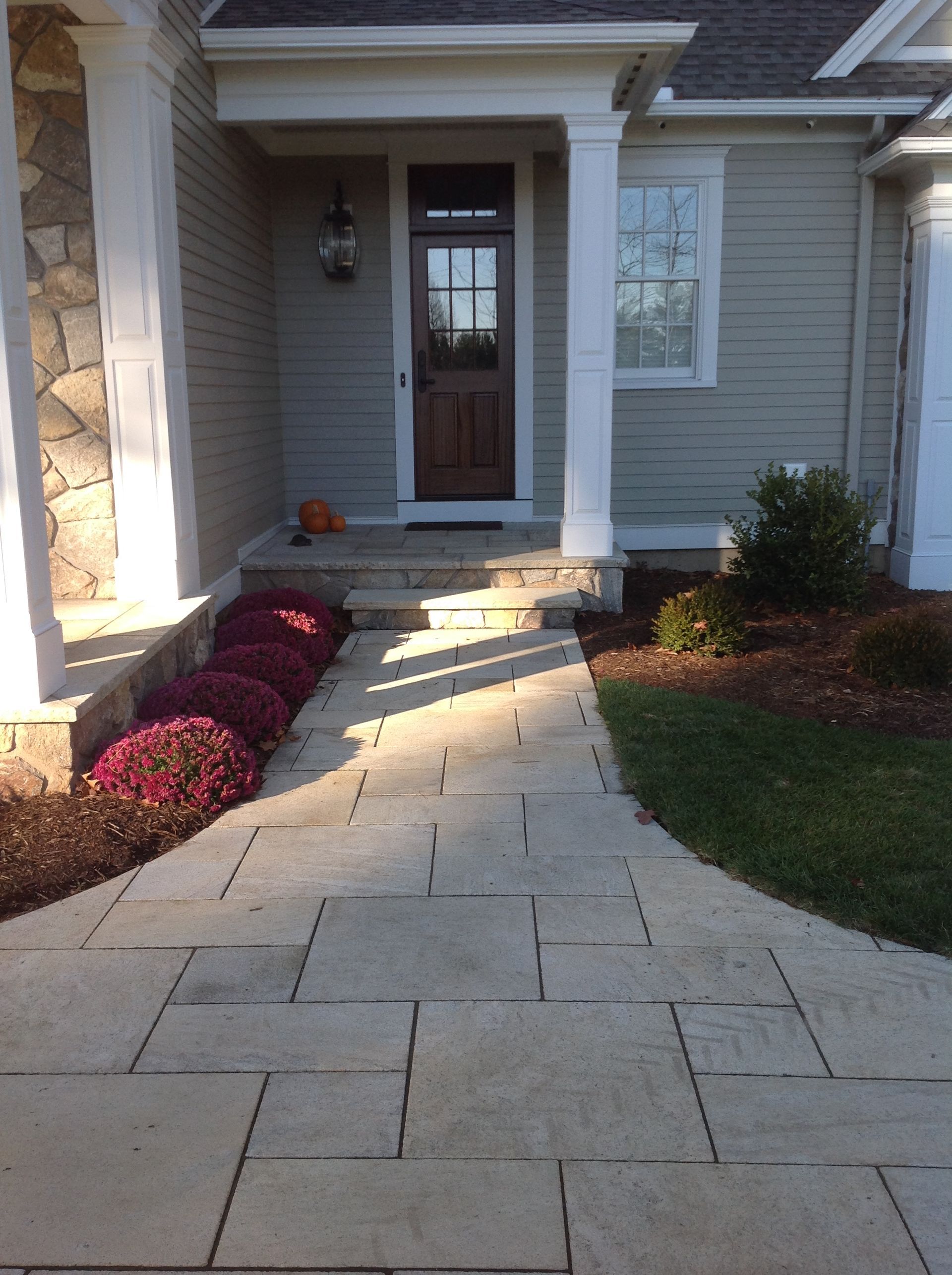 Stone path leading to a home's front door; mums line the walkway.