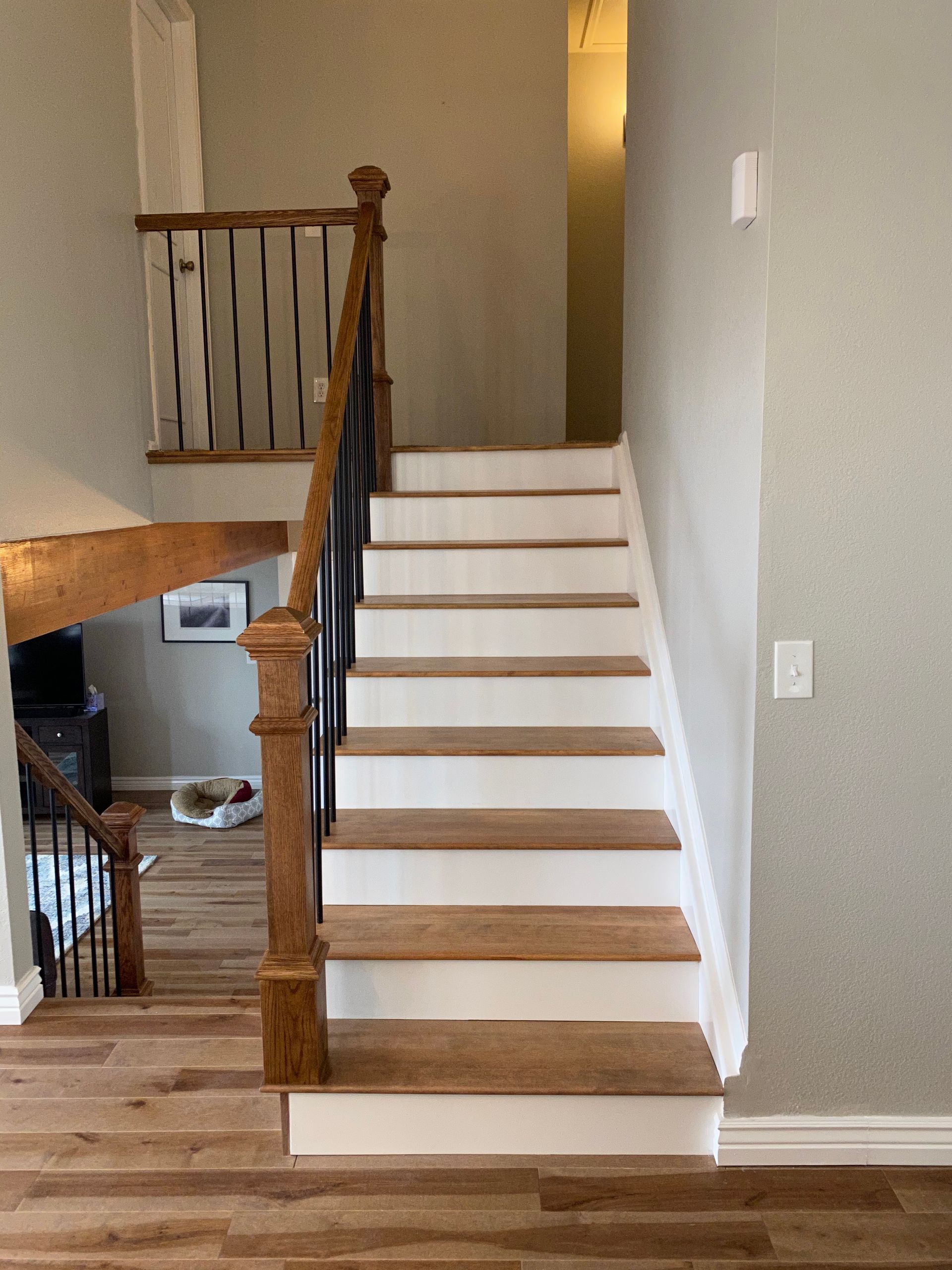 Interior staircase with white steps, wood trim, and black railing in a home hallway