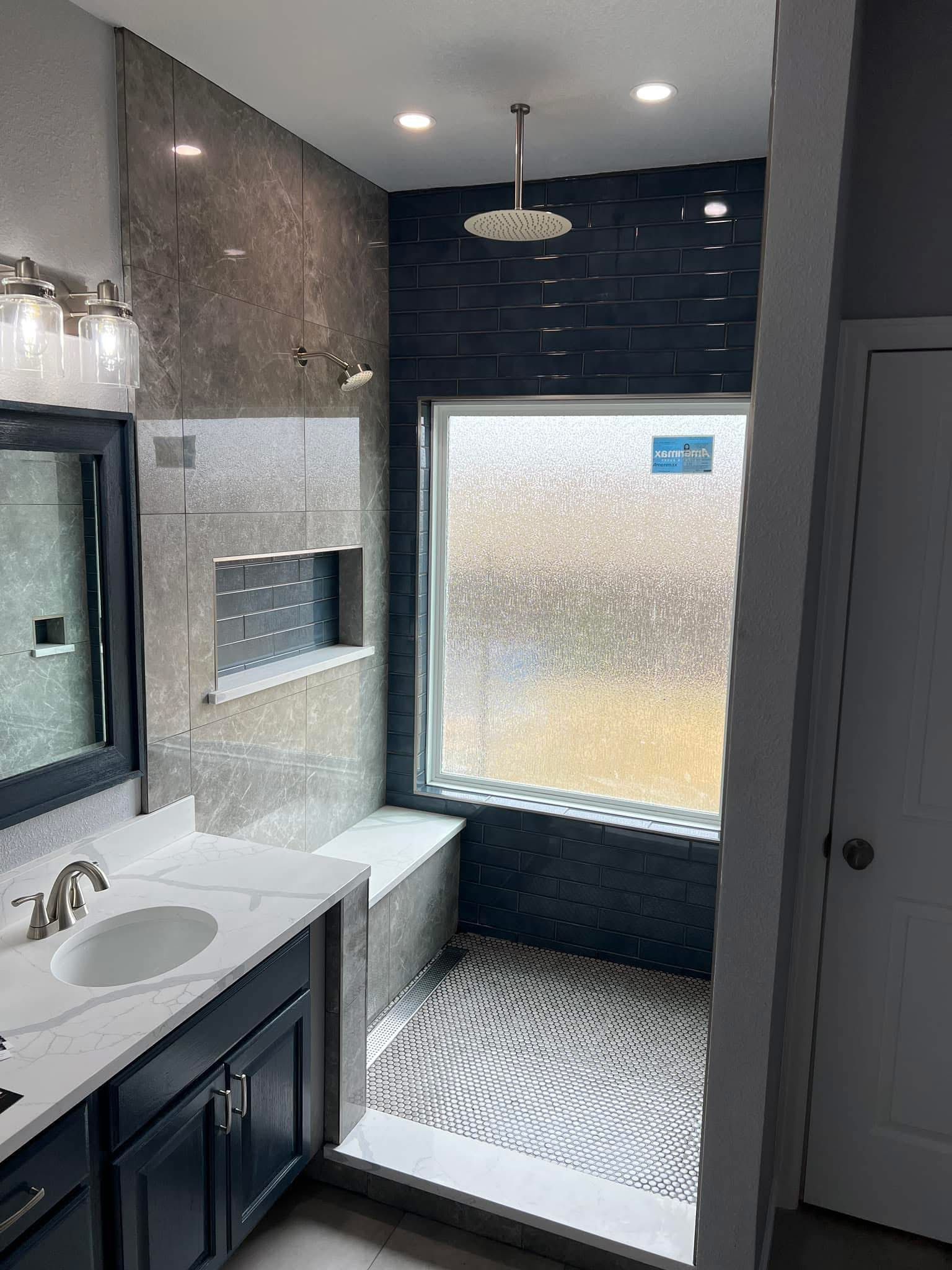 Modern bathroom with double sink, tiled shower, and frosted glass window.