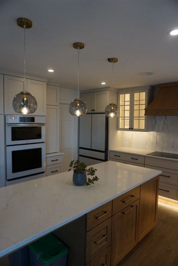 Modern kitchen with large island, pendant lights, built-in ovens, and warm under-cabinet lighting