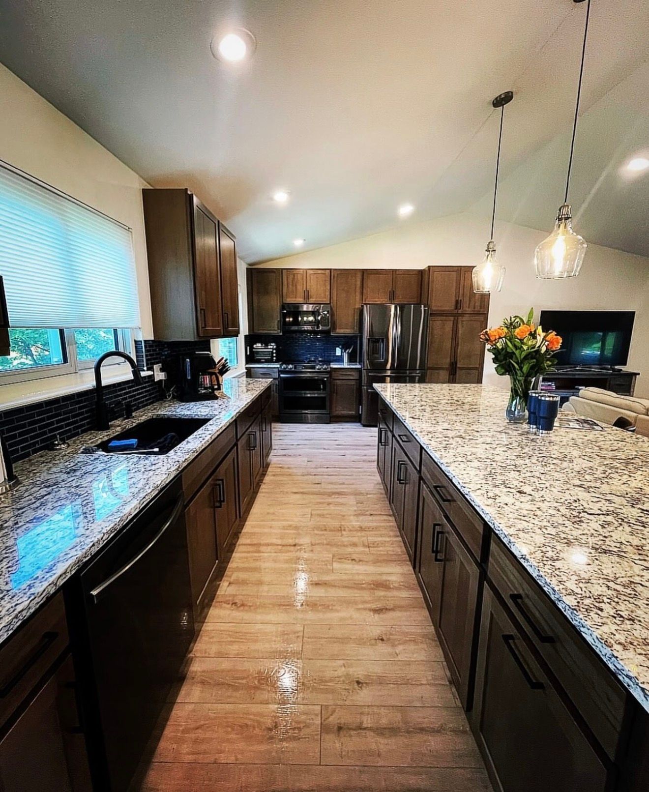 Modern kitchen with dark wood cabinets, granite countertops, stainless appliances, and pendant lights.