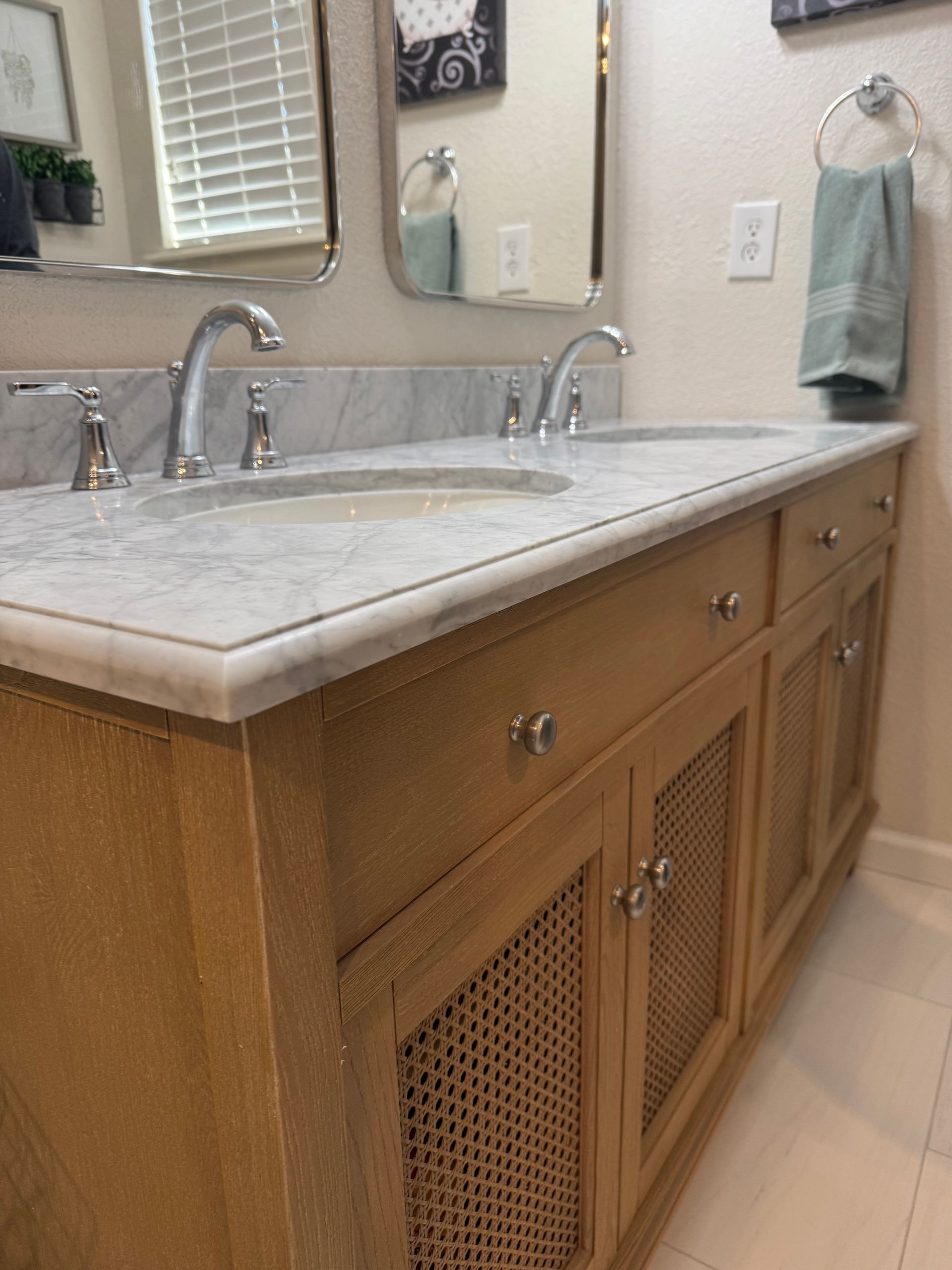 Bathroom vanity with marble countertop, sink, faucet, and wooden cabinet doors with woven panels.