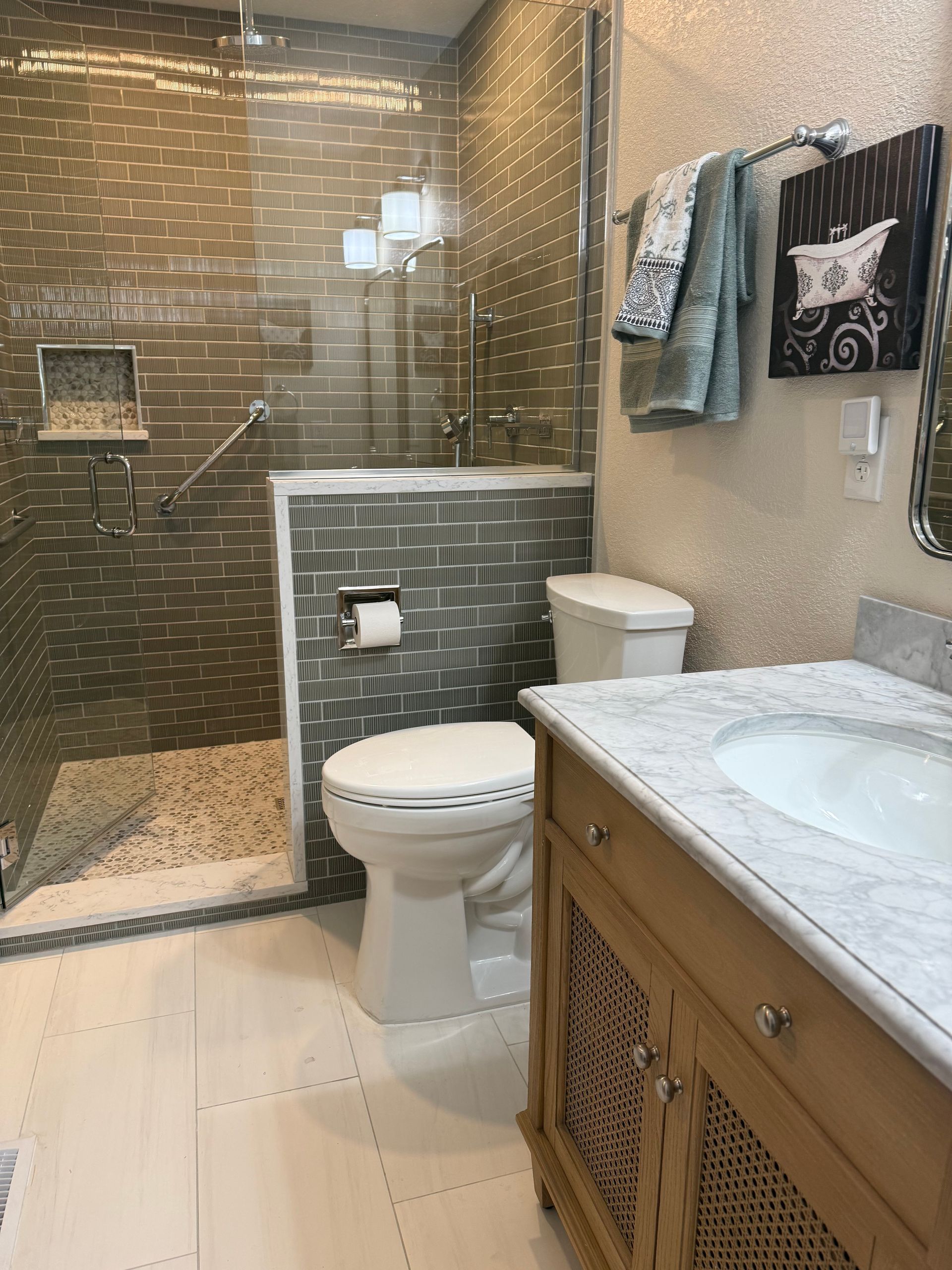 Modern bathroom with glass shower, toilet, and wood vanity with white sink.