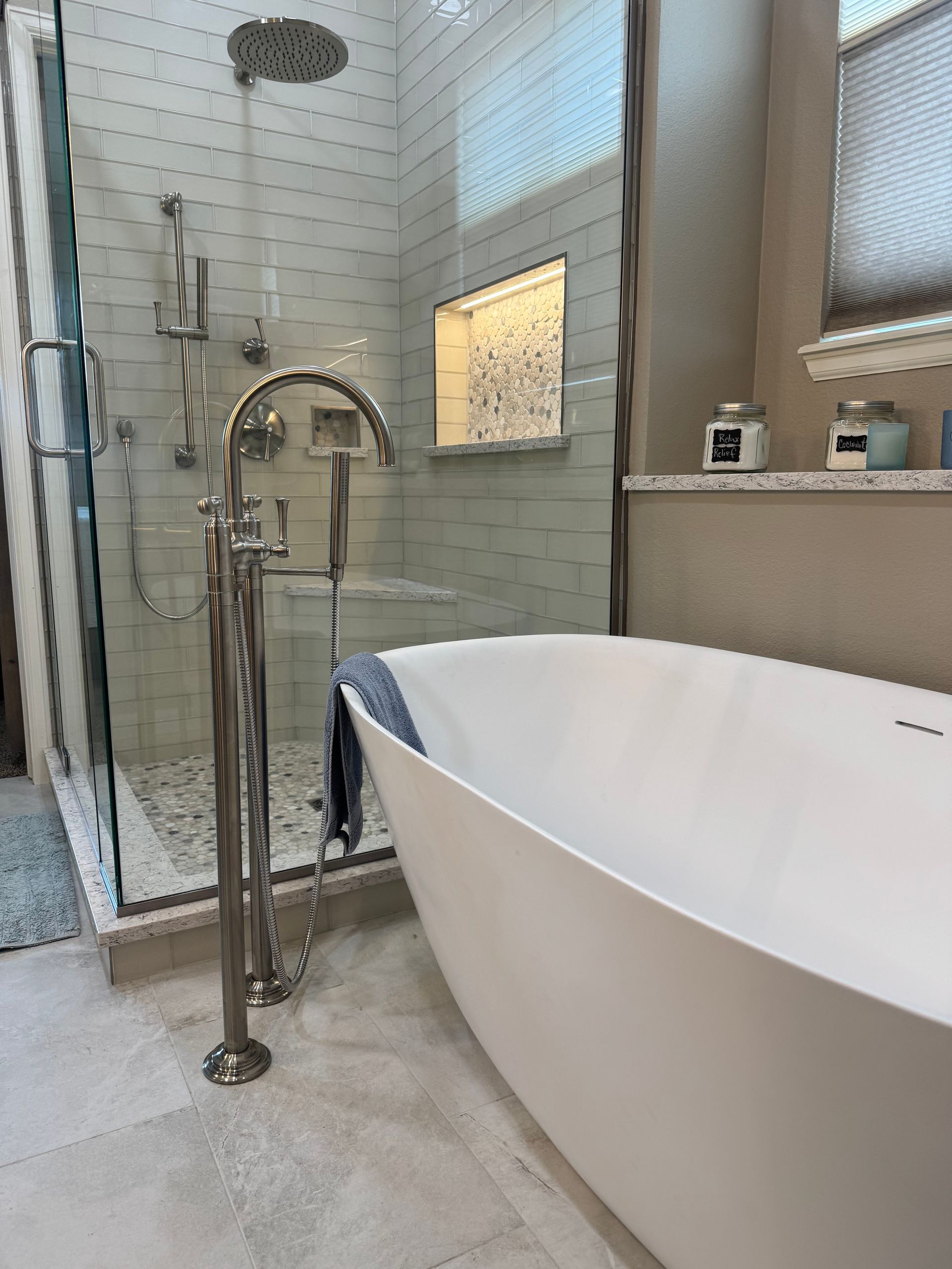 Modern bathroom with a freestanding tub and glass shower, featuring chrome fixtures and white tile walls
