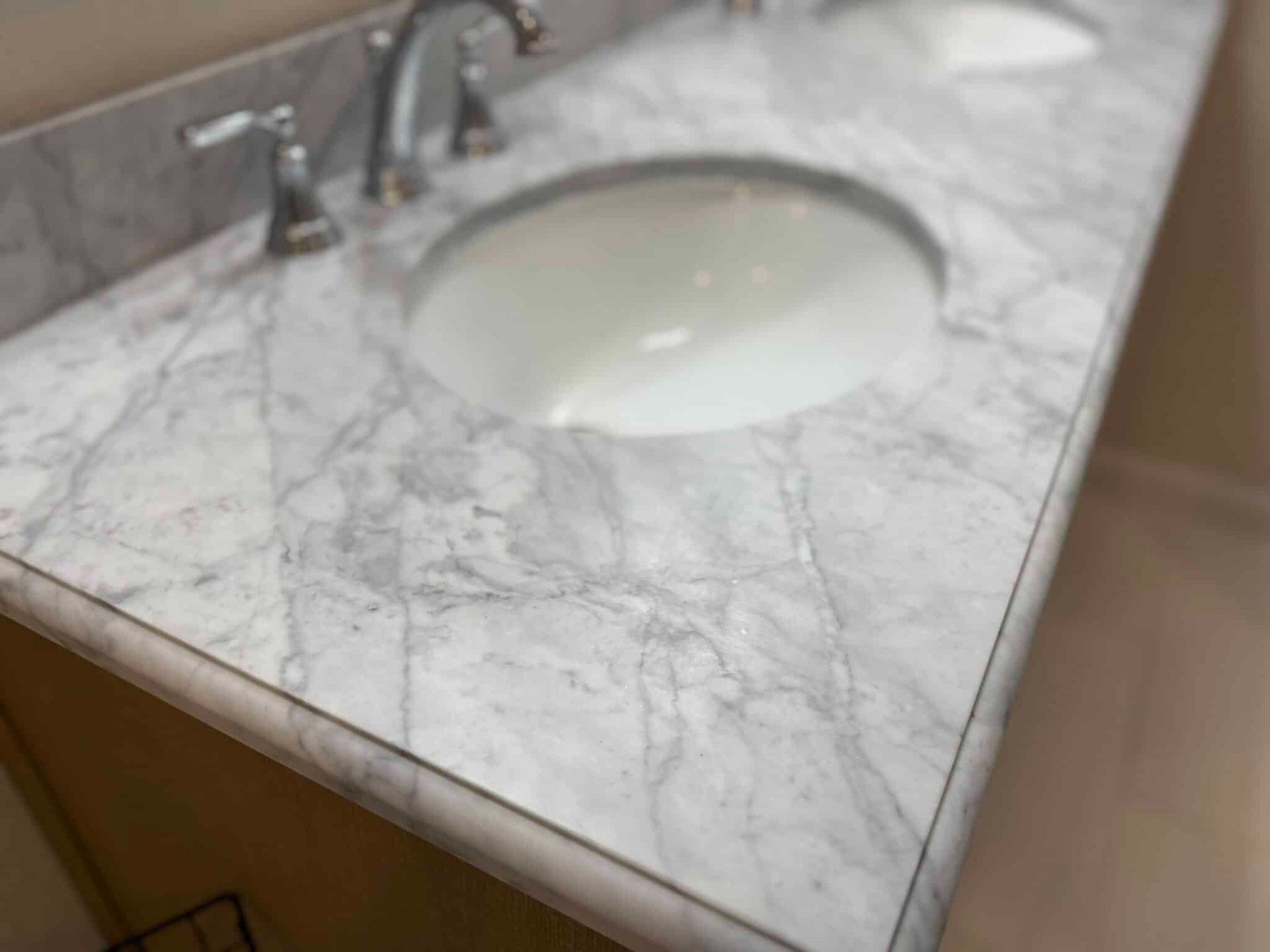 White marble bathroom vanity with round sink and chrome faucet