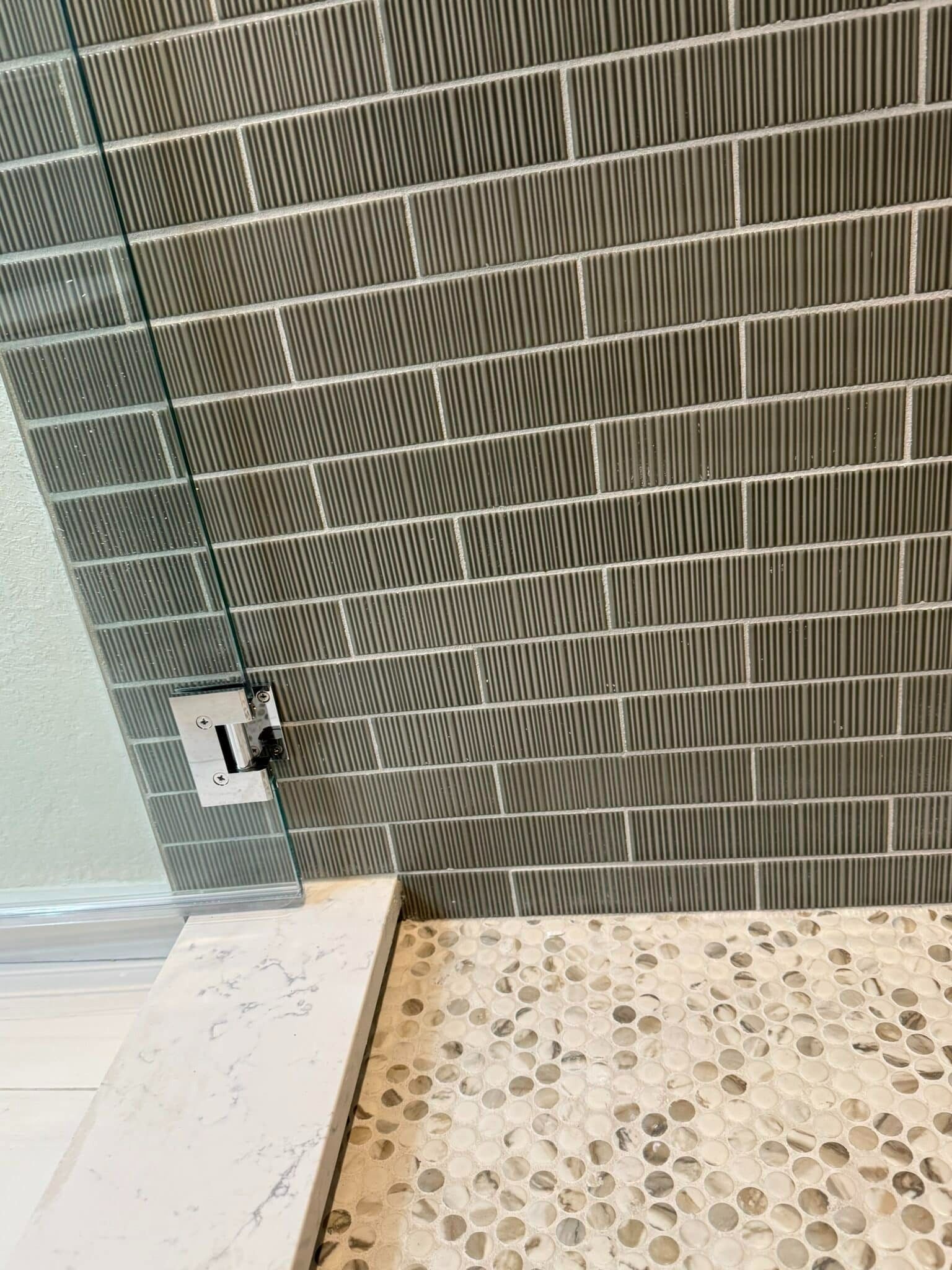 Tiled bathroom corner with wall paneling, a floor drain, and a small electrical outlet near the baseboard