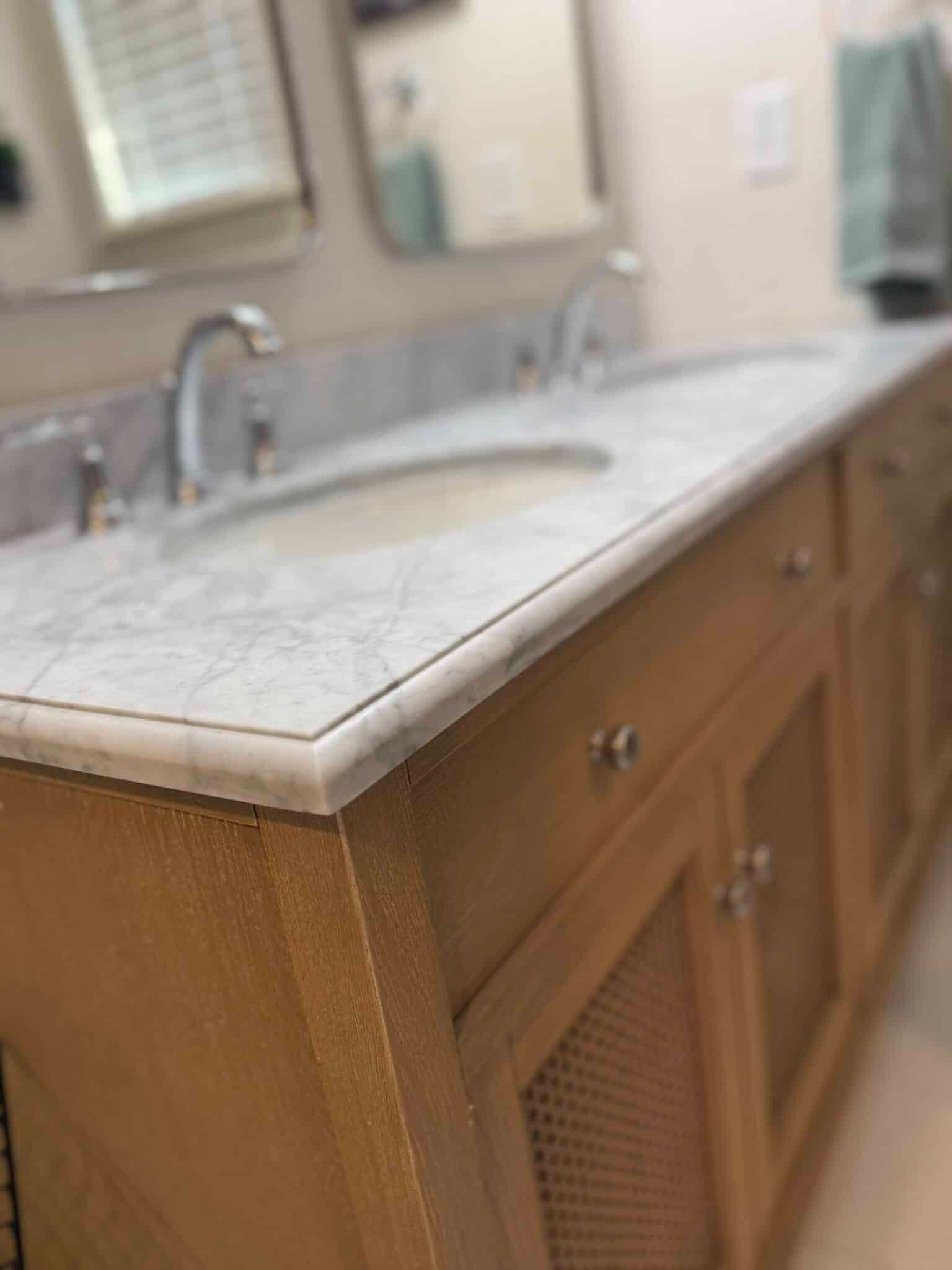 Bathroom vanity with marble countertop, sink, and wooden cabinet doors