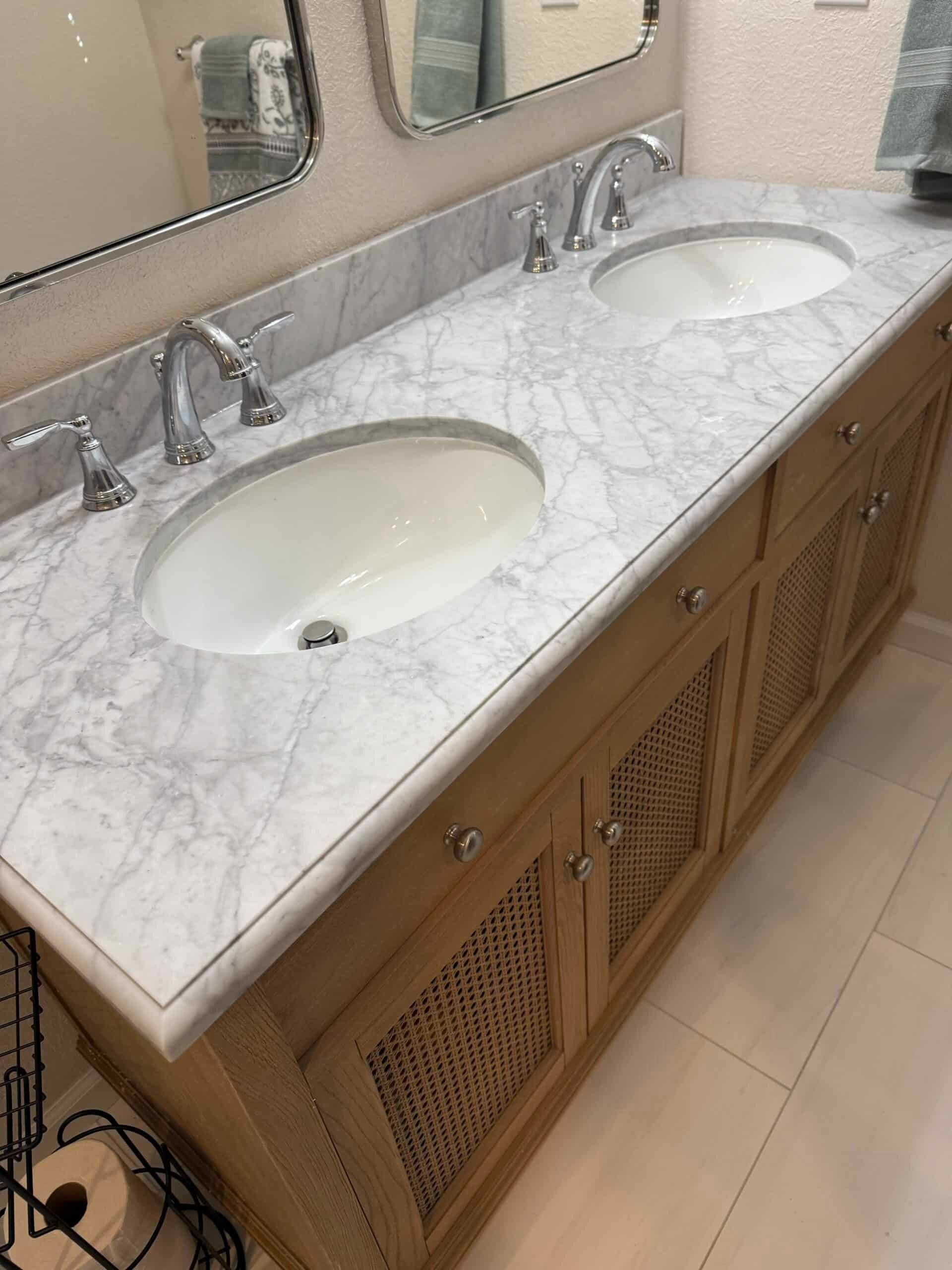 Double-sink bathroom vanity with marble countertop and wooden cabinets beneath mirrors