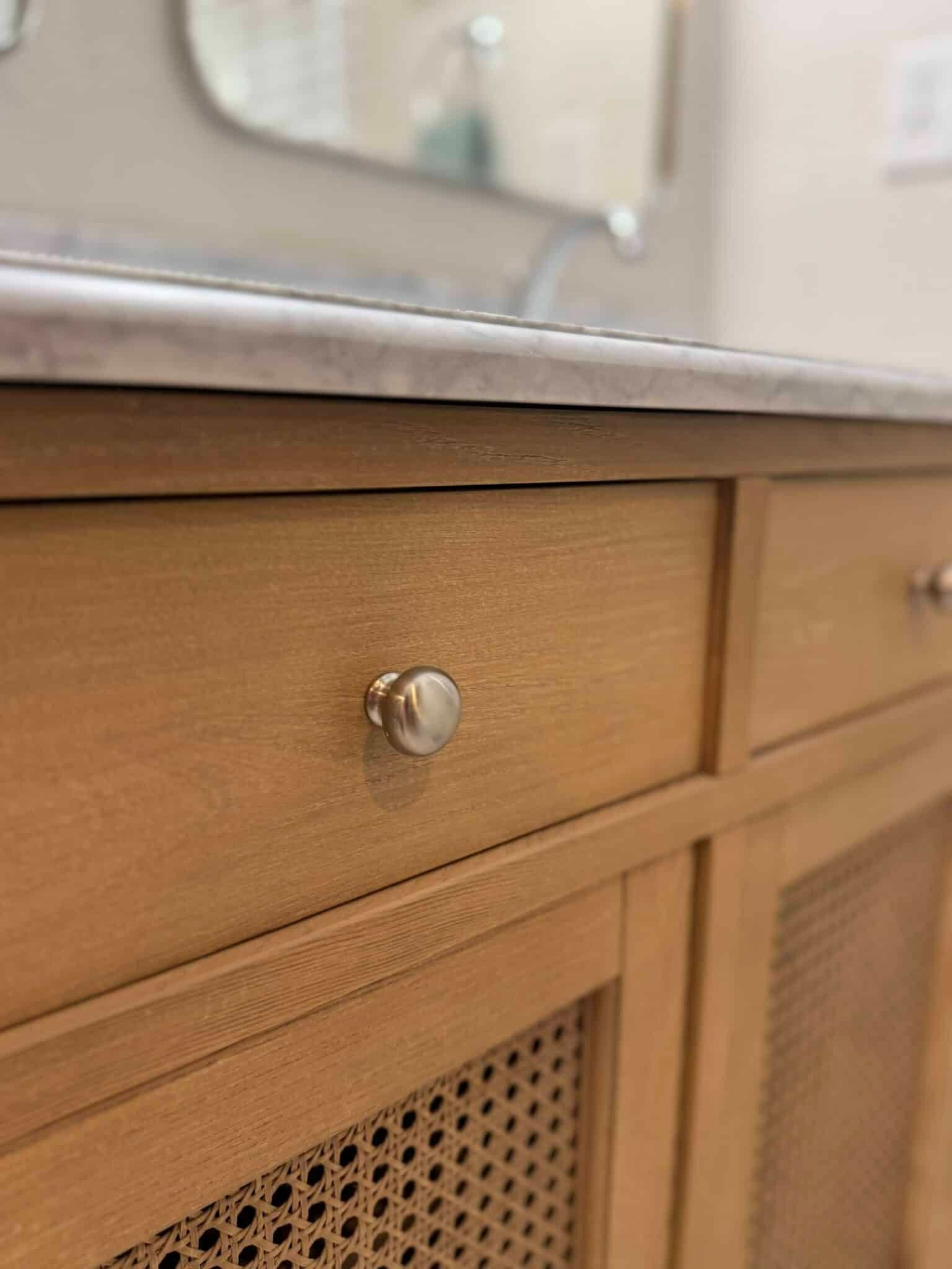 Wooden bathroom vanity drawer with a round silver knob beneath a countertop countertop edge.
