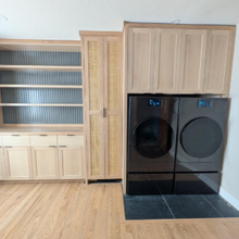Laundry room with built-in cabinets, shelving, and black front-loading washer and dryer on a light wood floor