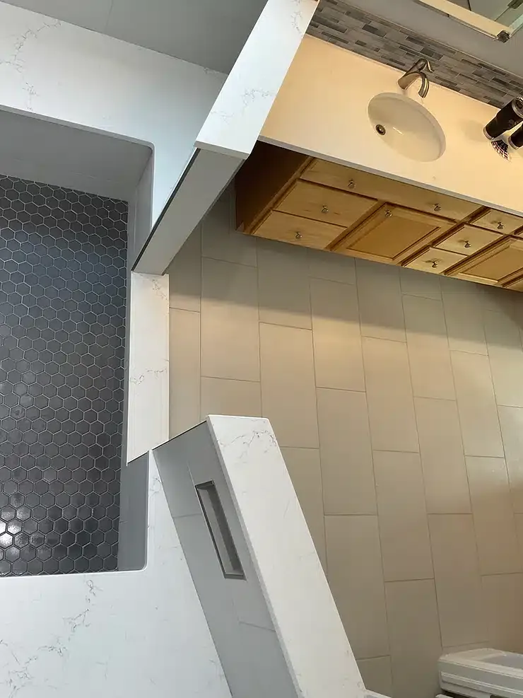 Indoor ceiling area with exposed beams, white panels, and gray tiled wall sections