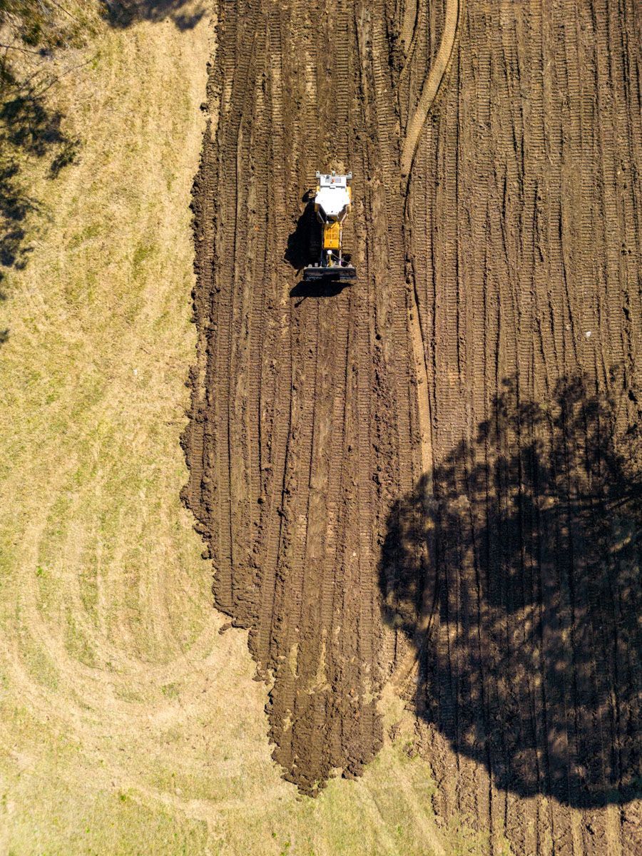 An aerial view of a person plowing a field with a tractor.
