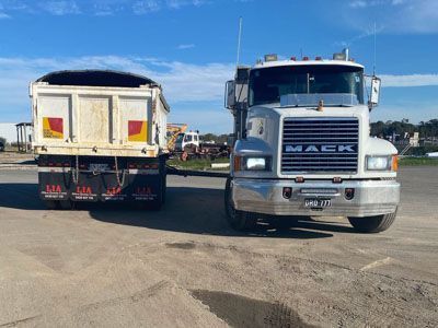Two mack trucks are parked next to each other in a parking lot.