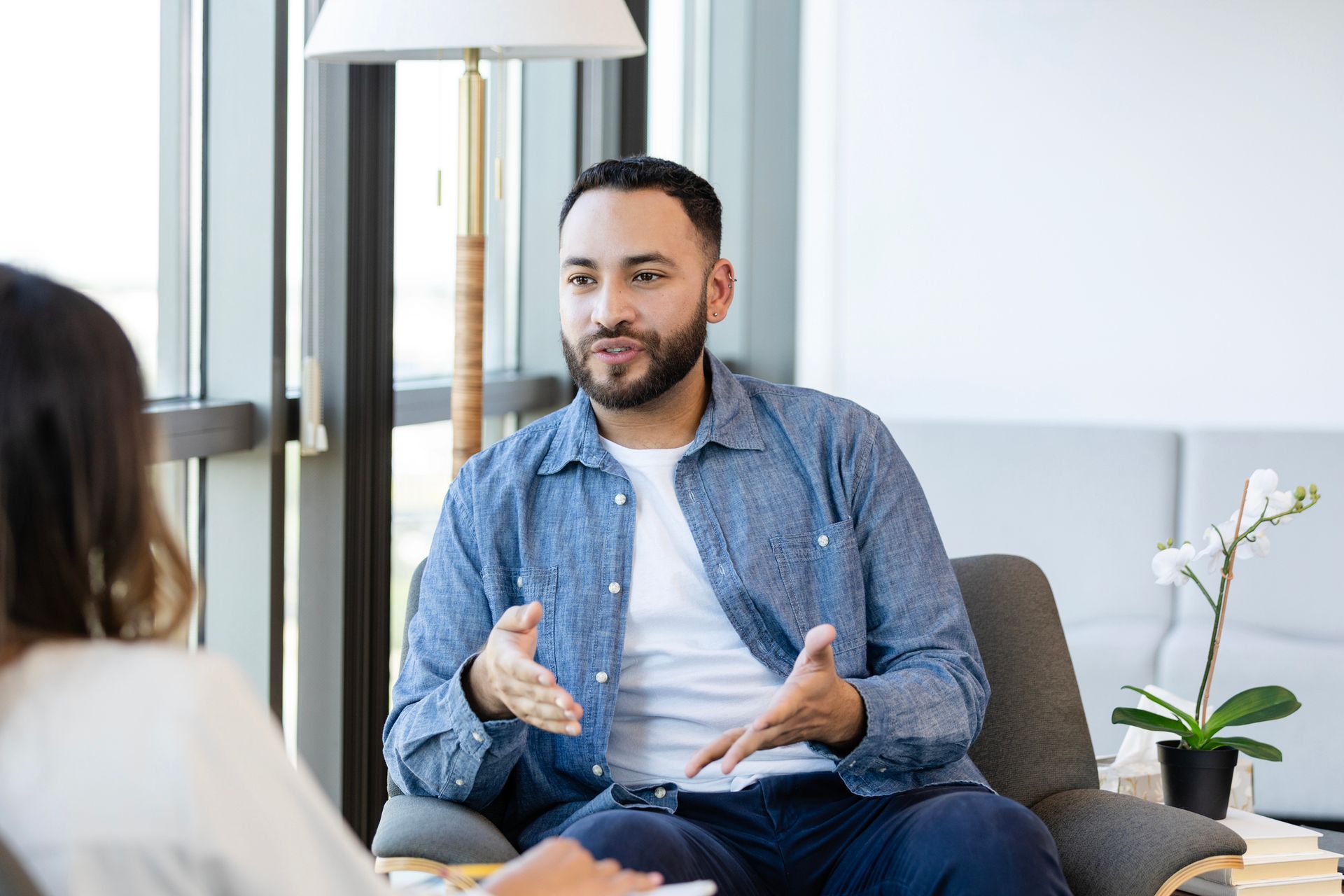 A man is sitting in a chair talking to a woman.