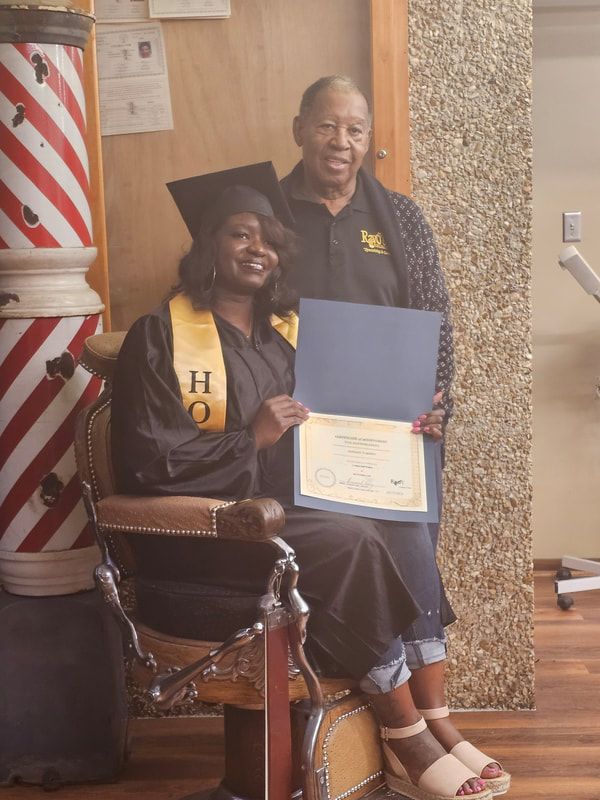 A woman in a graduation cap and gown is sitting in a barber chair