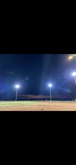 Nighttime outdoor field lit by bright floodlights under a dark sky.