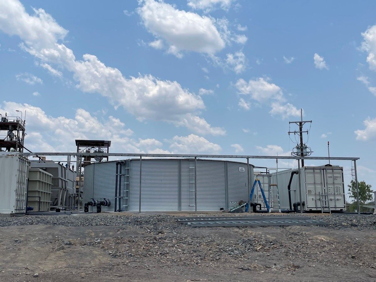 Industrial facility with metal tanks and structures under a blue sky with clouds