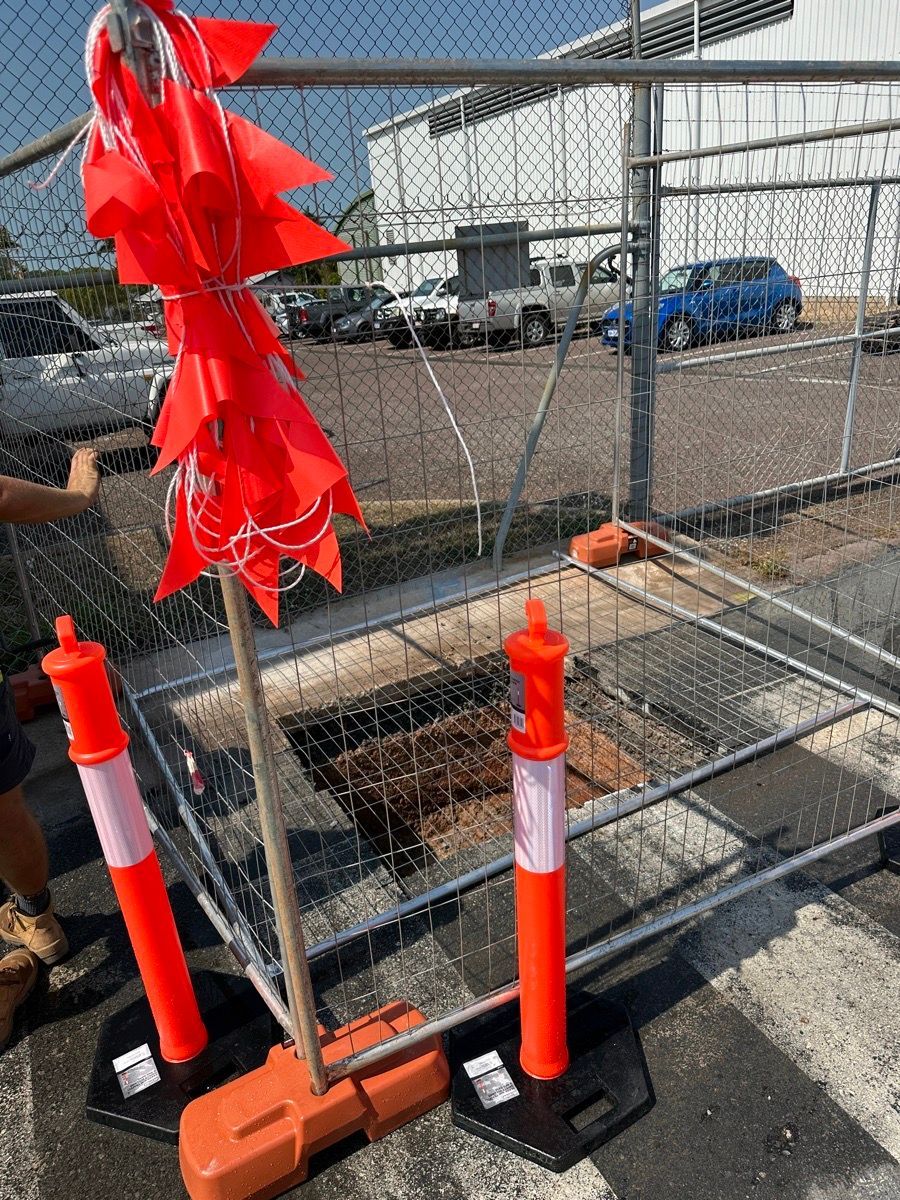 Red wind spinners on black bases beside a fenced railroad crossing construction area