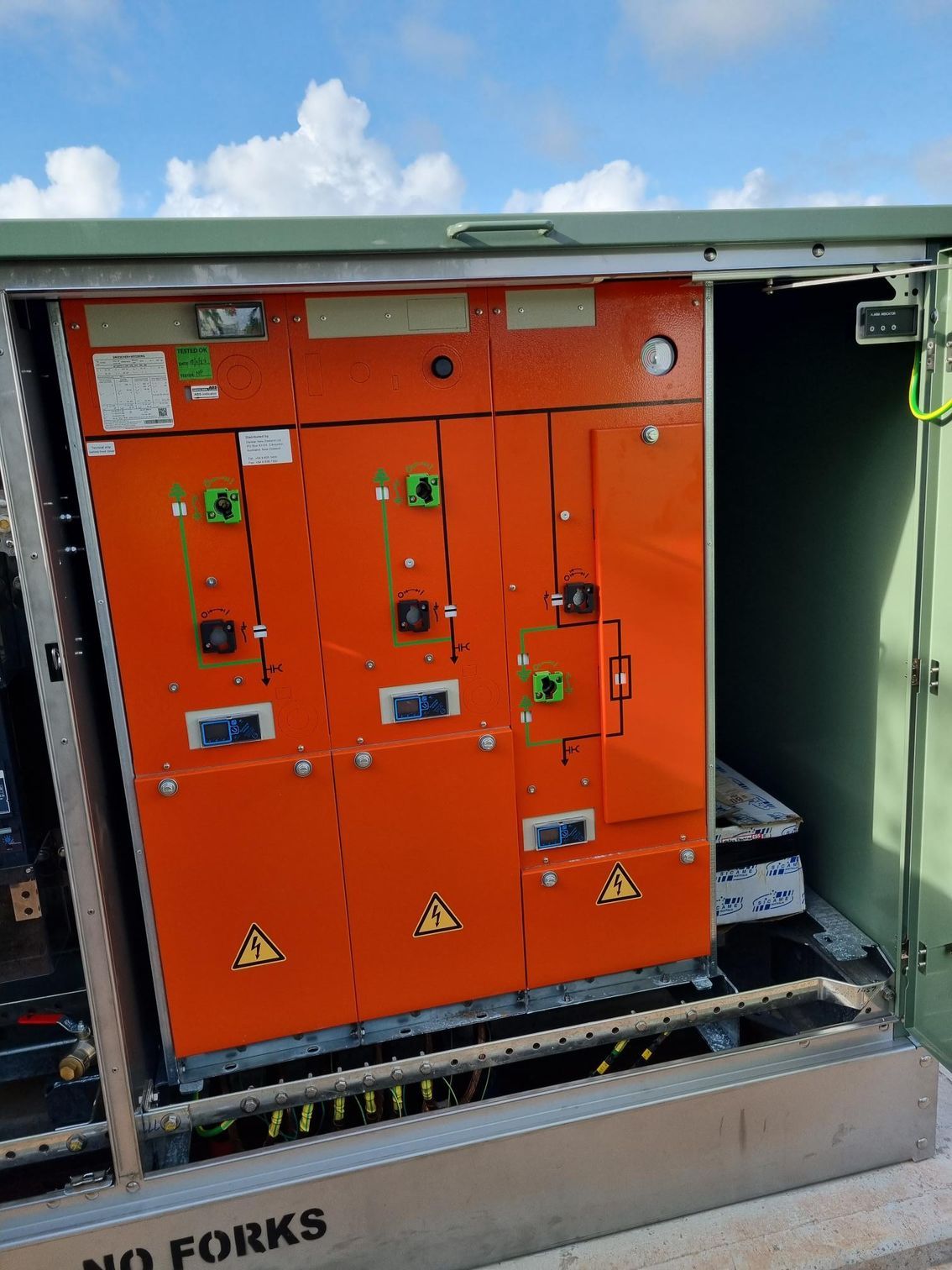Orange electrical control cabinet inside a metal enclosure labeled “NO FORKS.”
