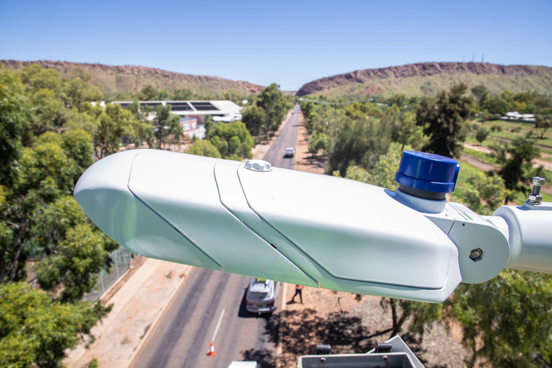 Aerial traffic sensor overlooking a road lined with trees and desert hills