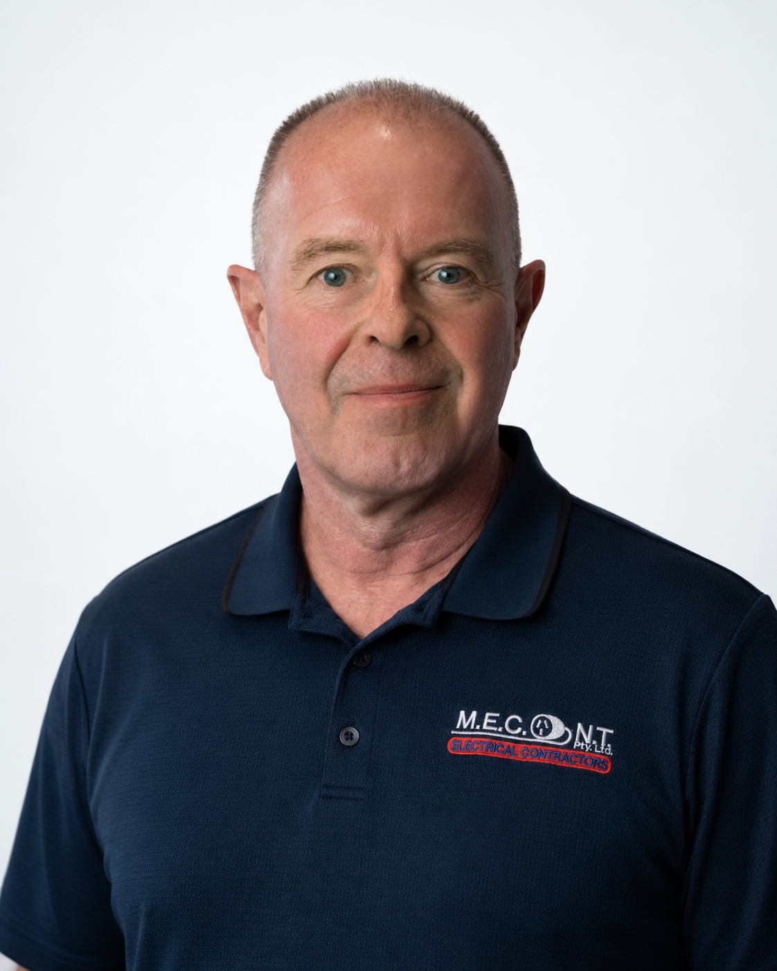 Portrait of a man in a navy polo shirt with a logo, standing against a plain white background.